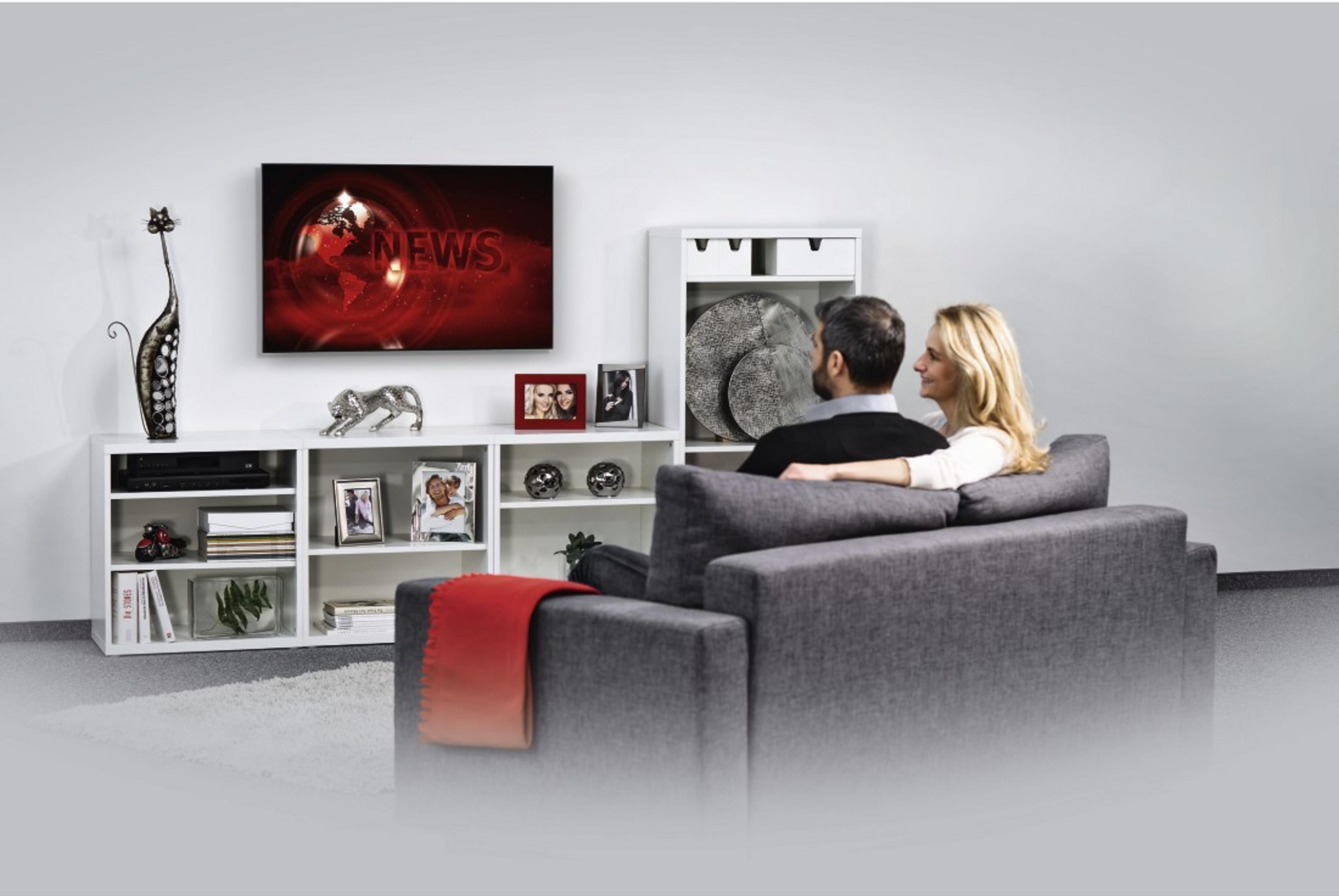 Una pareja ve las noticias en un televisor en una sala.