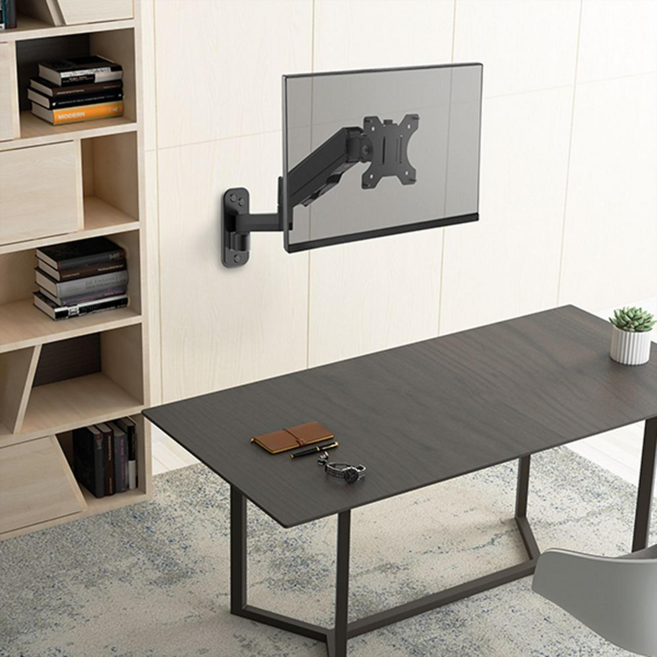 Ein Schreibtisch mit einem Monitor, der an der Wand montiert ist. Ein Bücherregal steht links.