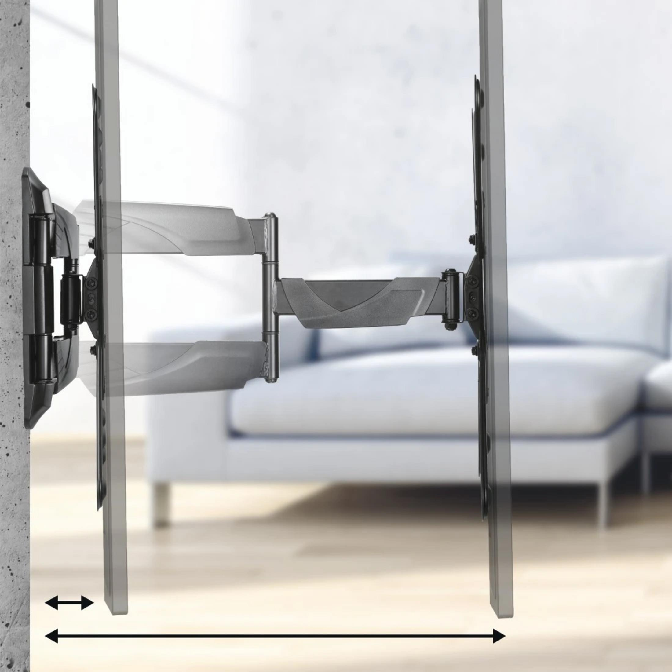 Ein schwenkbarer TV-Halter an einer Betonwand, daneben ein Sofa.
