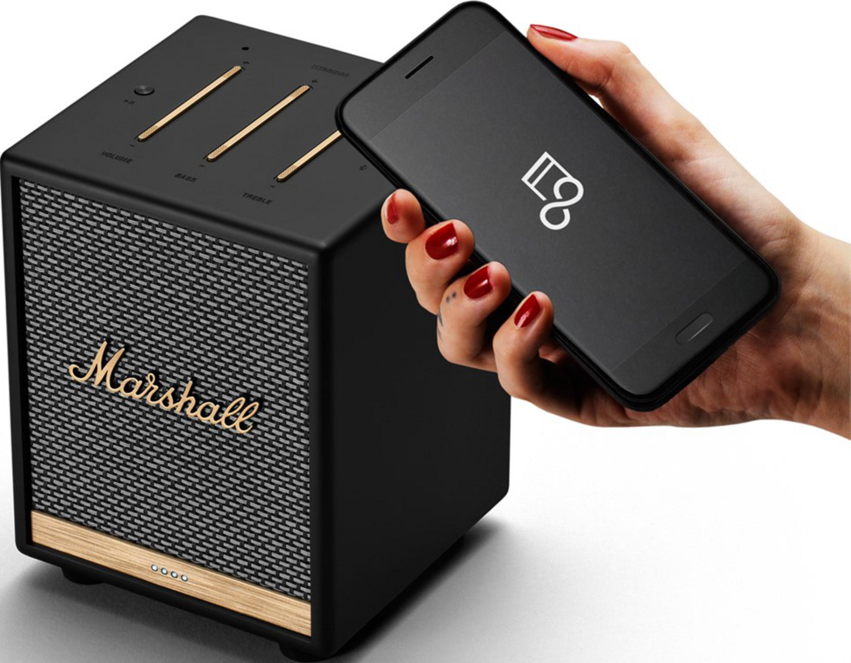 Una mano sostiene un smartphone sobre un altavoz Marshall.