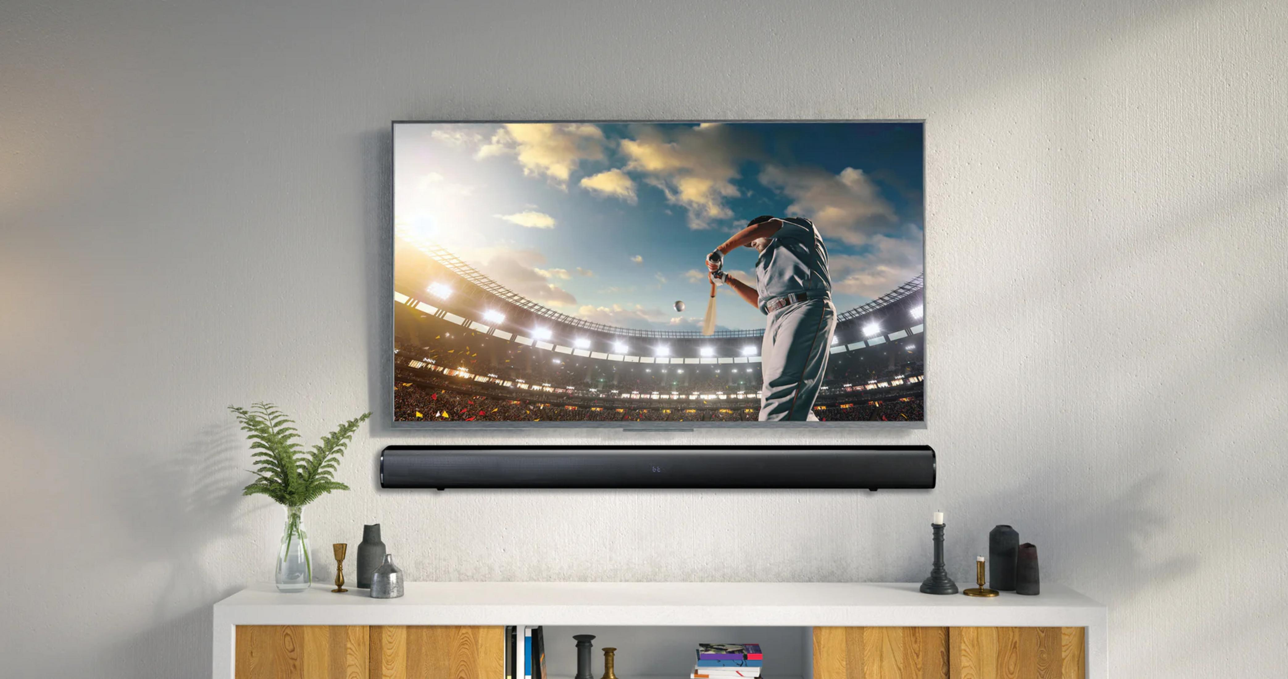 Ein Baseballspieler schwingt den Schläger vor einem vollen Stadion im Fernsehen, darunter eine Soundbar.