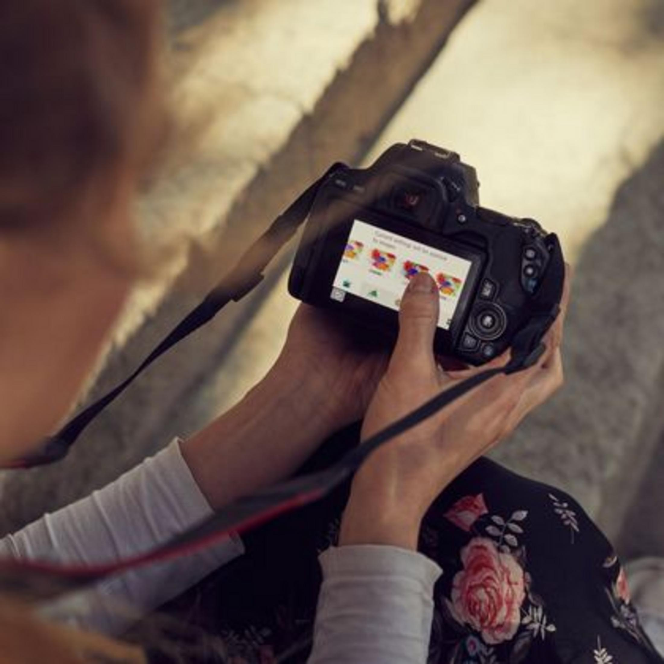 Person berührt den Bildschirm einer Kamera, die bunte Fotos anzeigt.