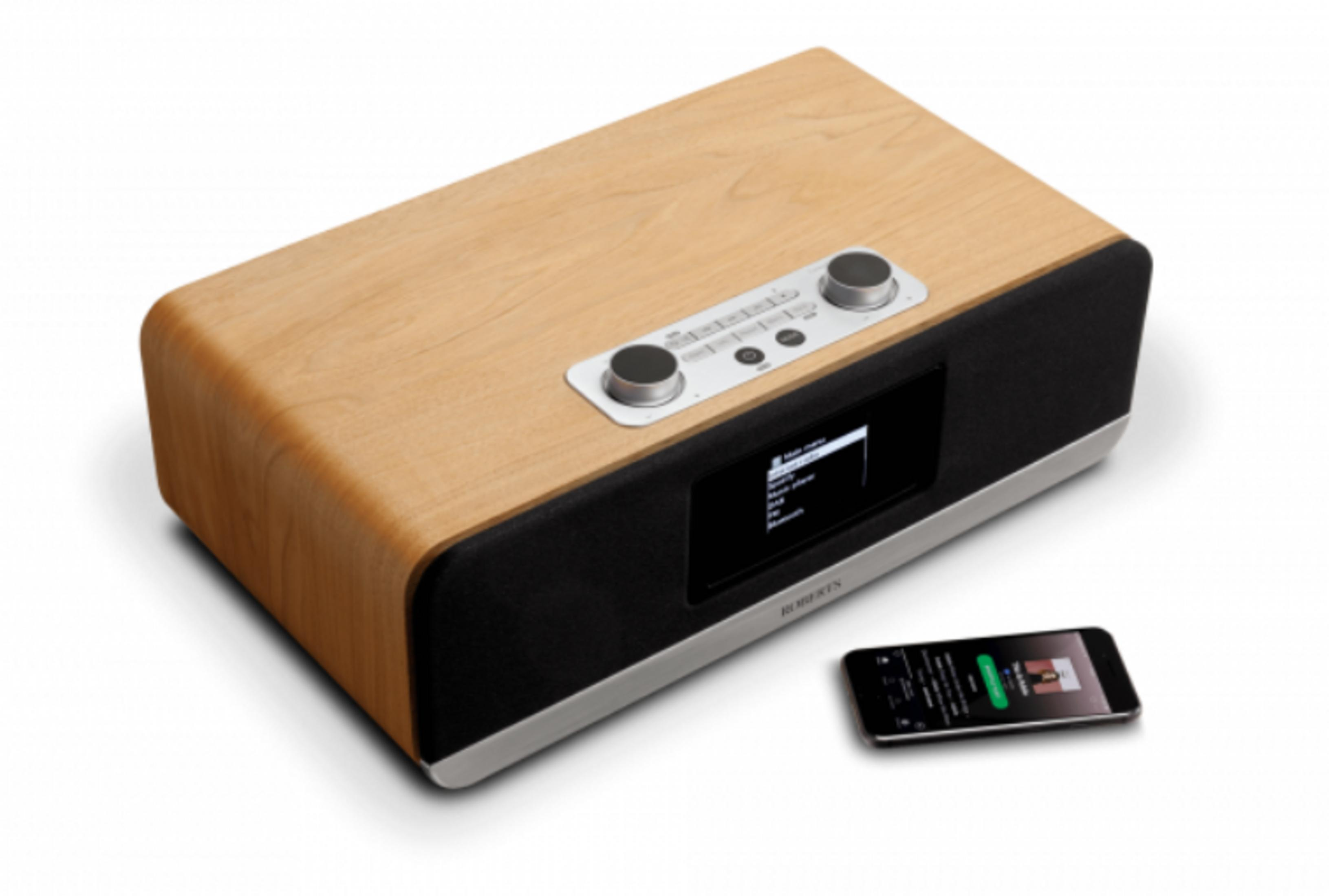 Ein Holzradio mit schwarzem Lautsprecher und einem Smartphone daneben.