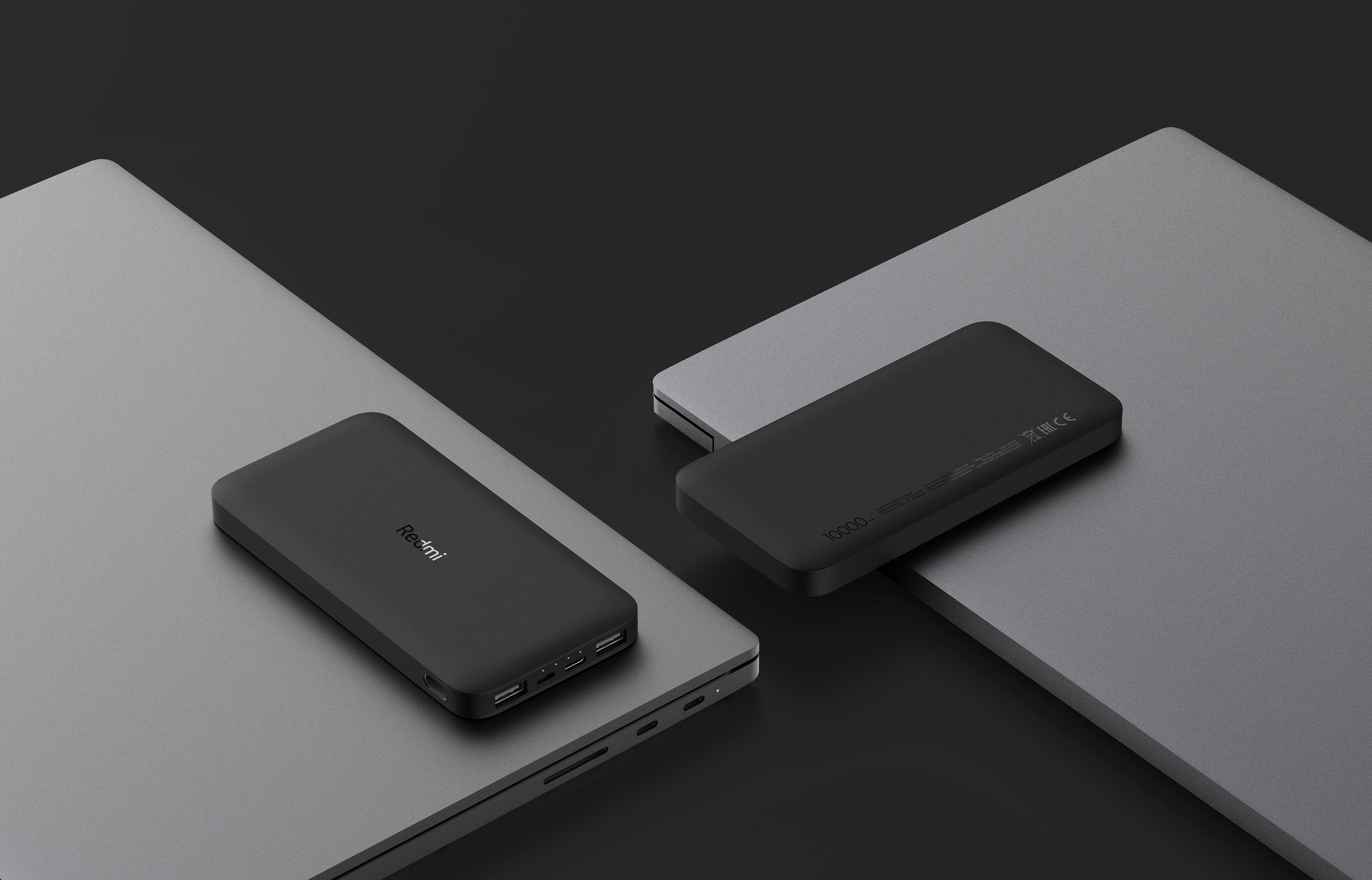 Koyu arka plan önünde gri dizüstü bilgisayarlar üzerinde iki siyah powerbank.
