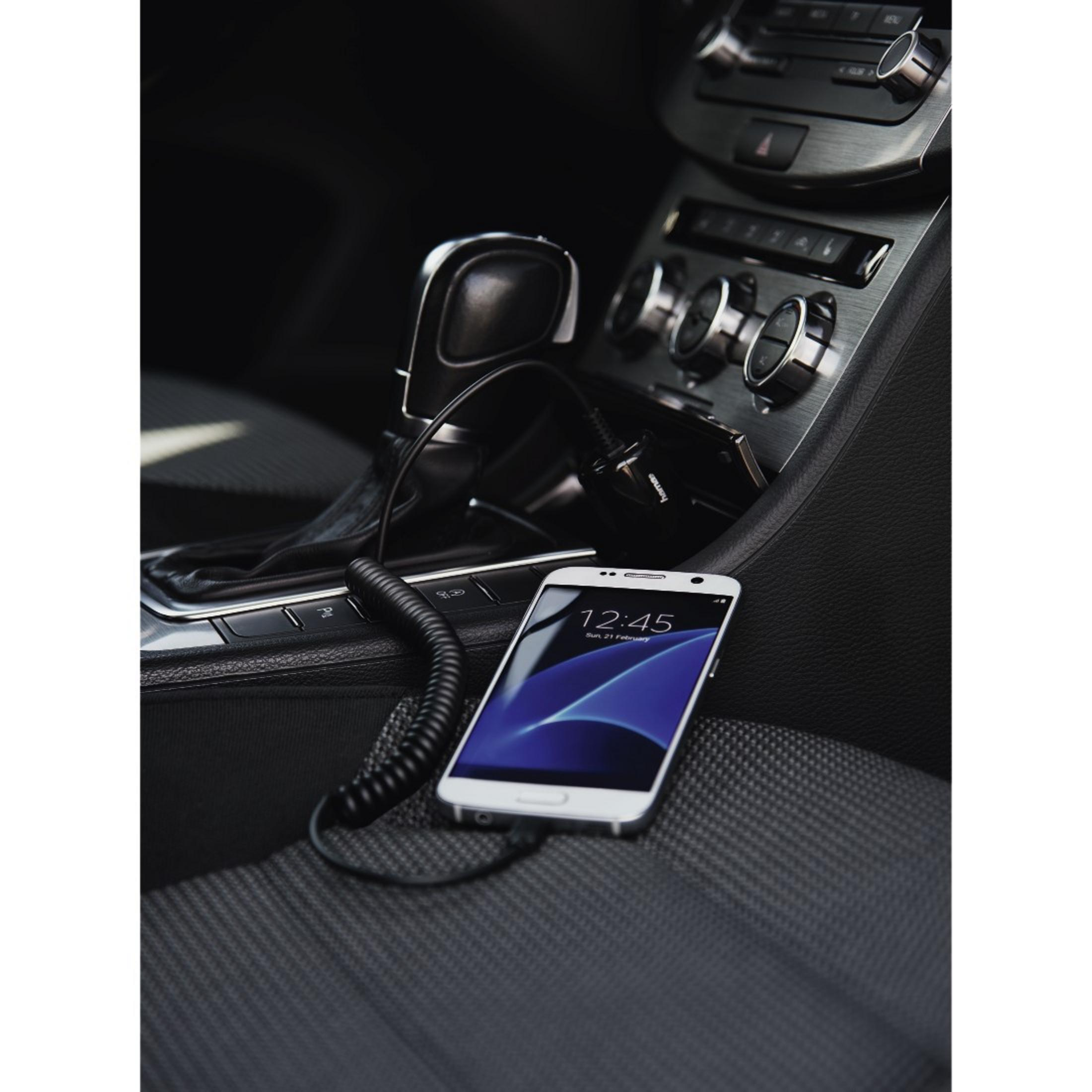 Ein weißes Smartphone wird im Auto aufgeladen, daneben der Schalthebel.