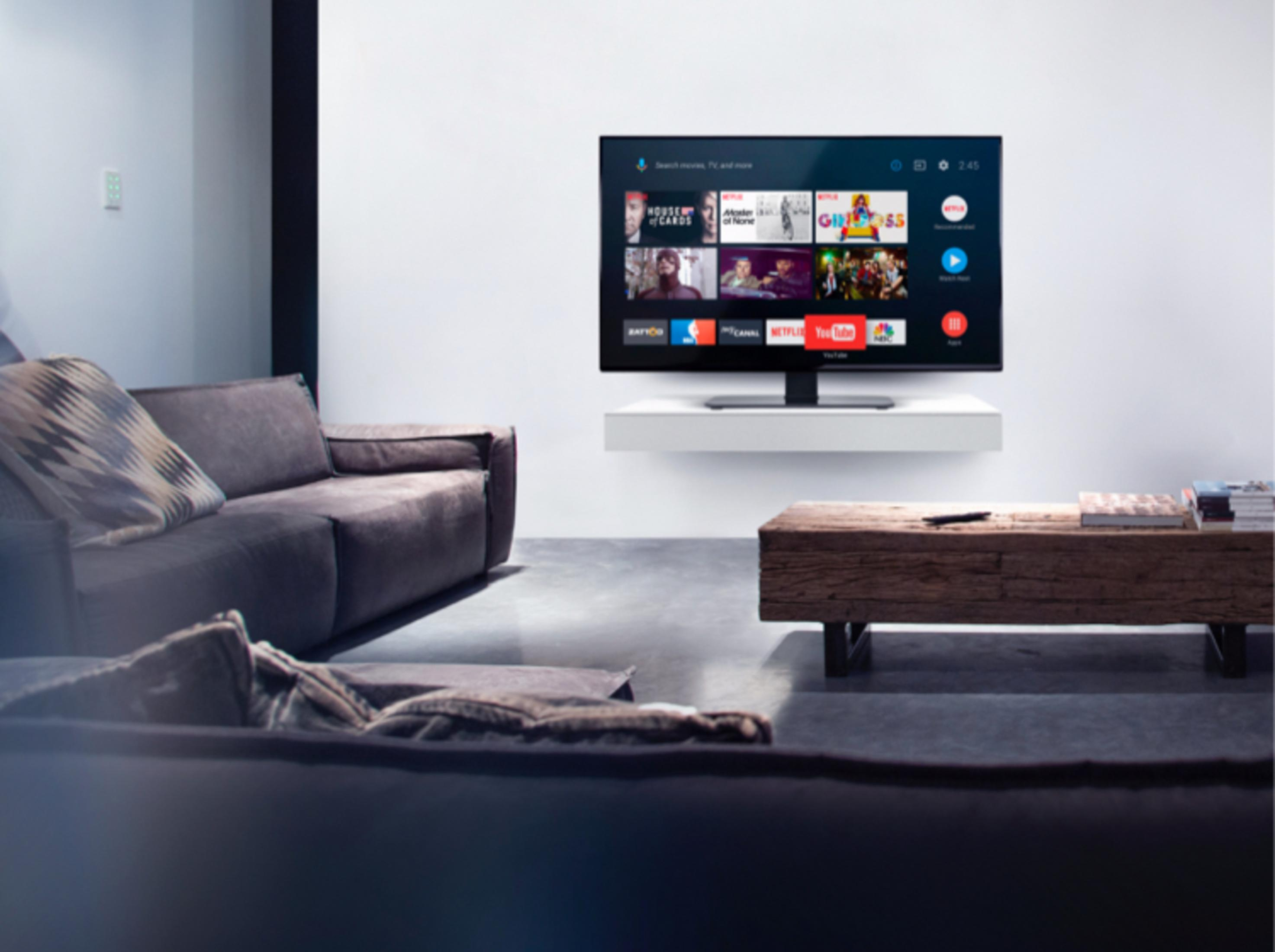Moderne woonkamer met donkere banken, houten tafel en smart-tv met apps.