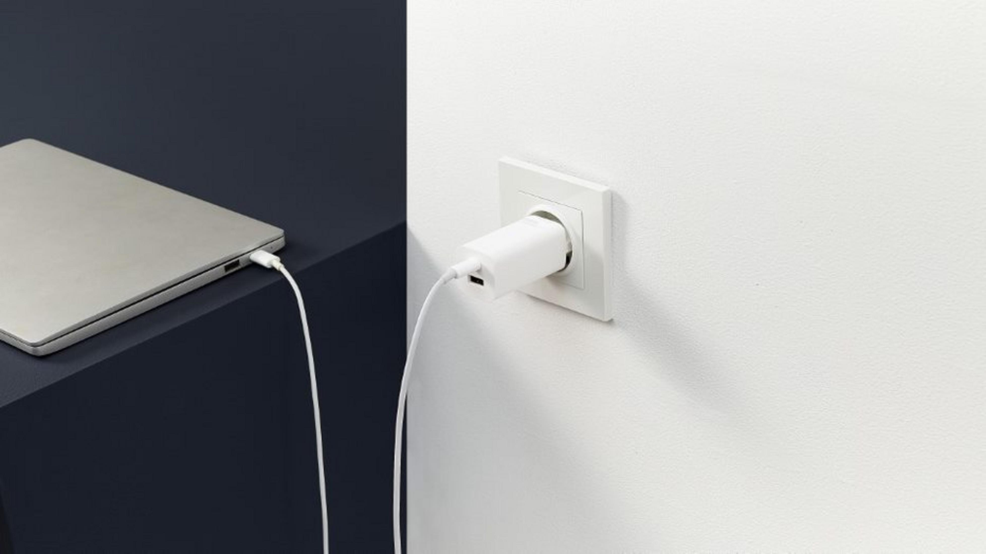 Een laptop wordt opgeladen via een witte USB-kabel die is aangesloten op een witte stekkeradapter.