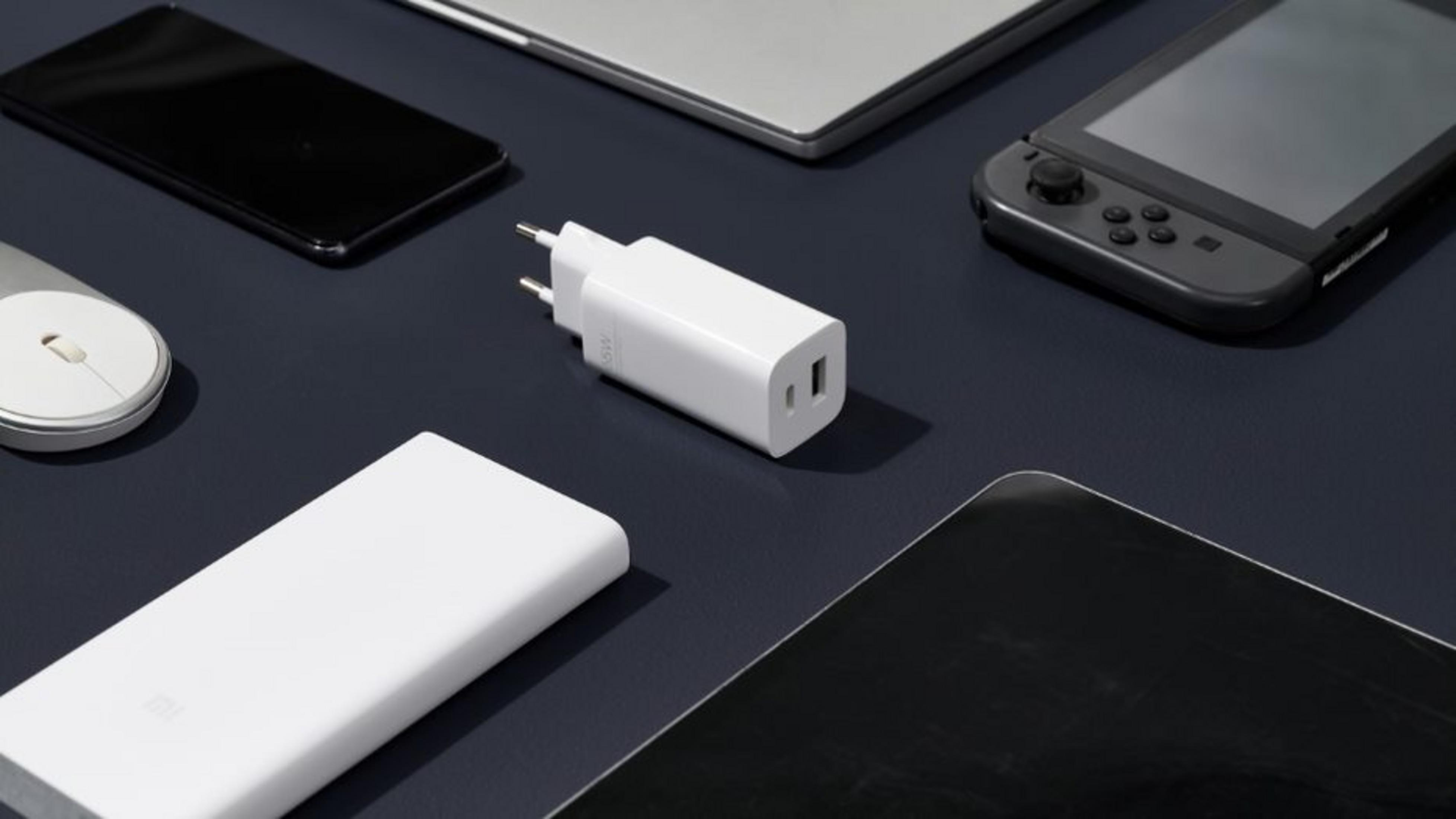 Witte opladers, smartphone, laptop, tablet, muis en spelconsole op een blauw oppervlak.