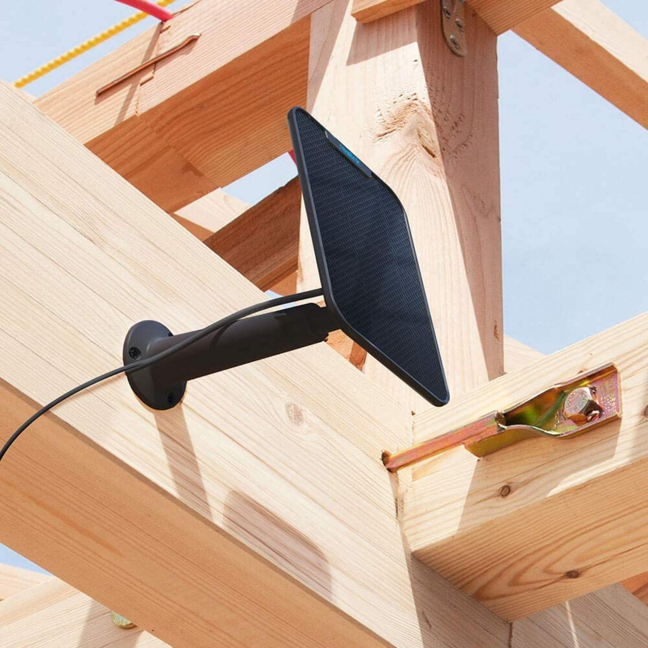 Schwarzes Solarpanel an Holzbalken montiert, mit Kabel und Metallhalterung.