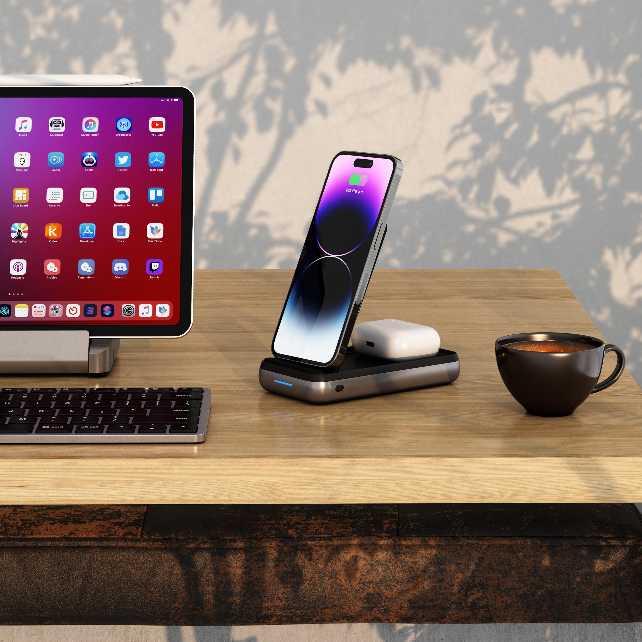 Ein iPhone lädt auf einer Ladestation neben einem Tablet, Tastatur und Kaffeetasse.