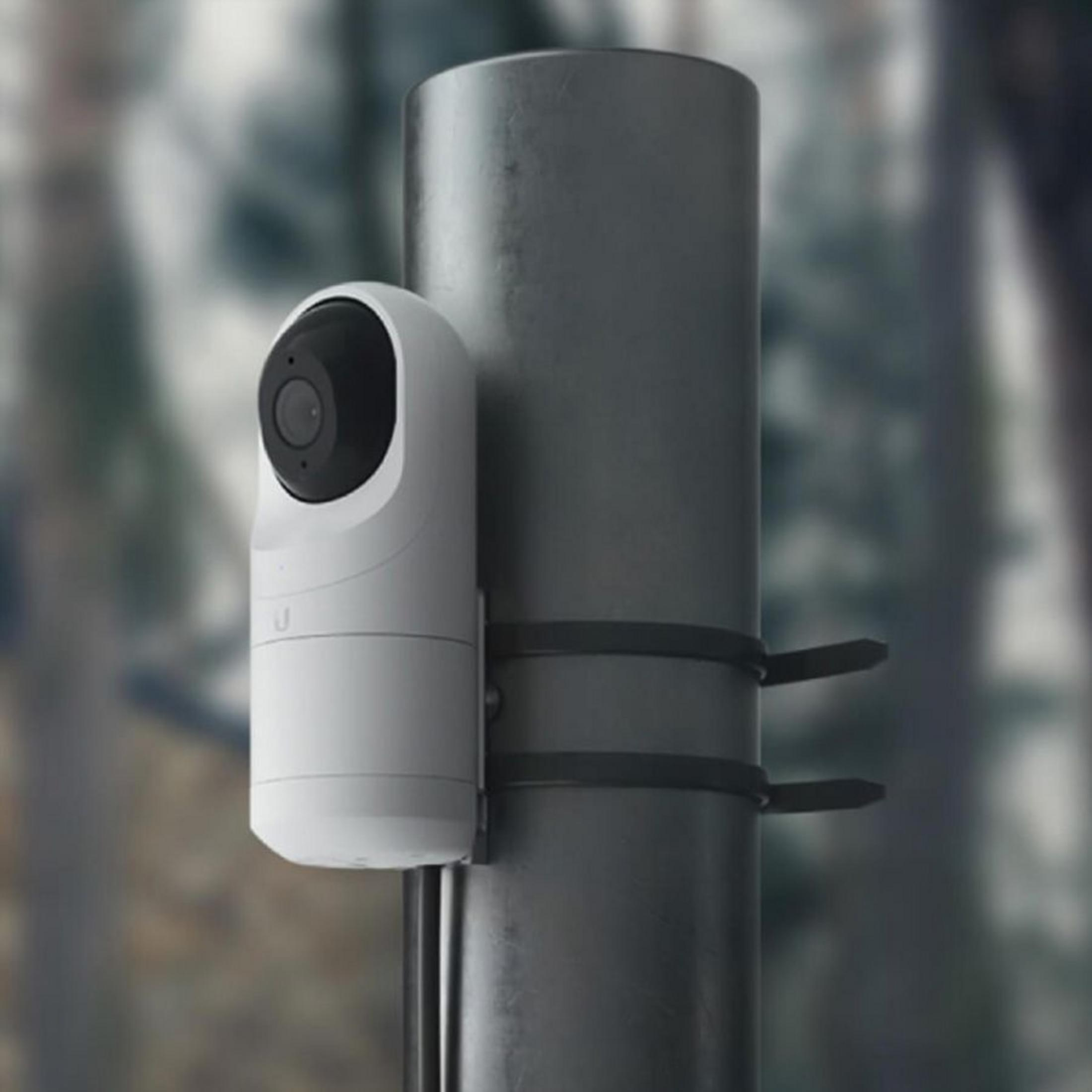 Una telecamera di sicurezza bianca è montata su un palo grigio.