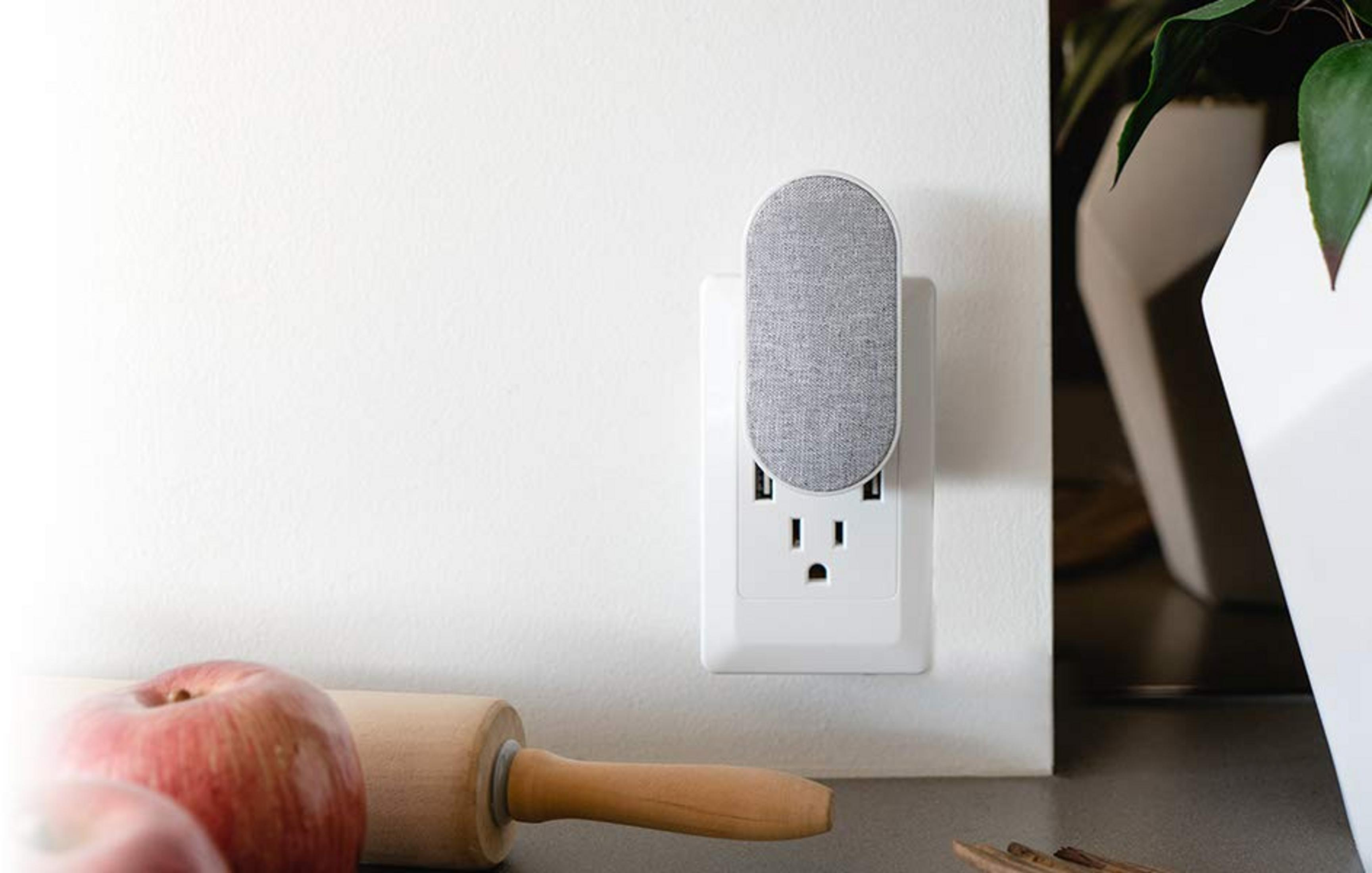 Grauer Stoffadapter in Steckdose mit zwei USB-Anschlüssen, daneben ein Nudelholz und Äpfel.