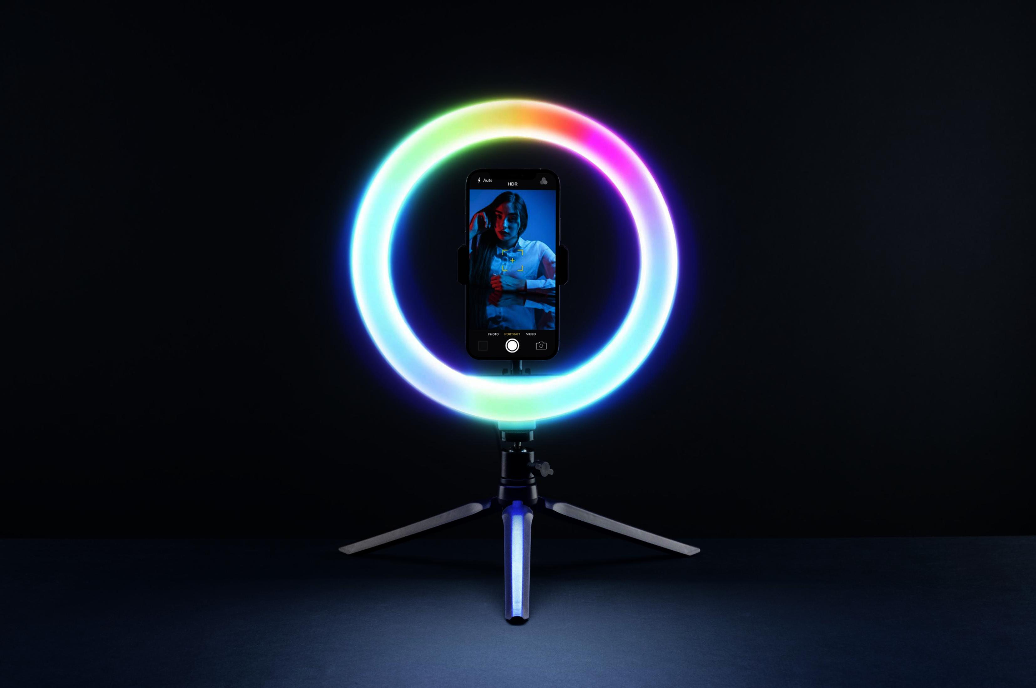 Un smartphone sobre un trípode, iluminado por una luz de anillo colorida.