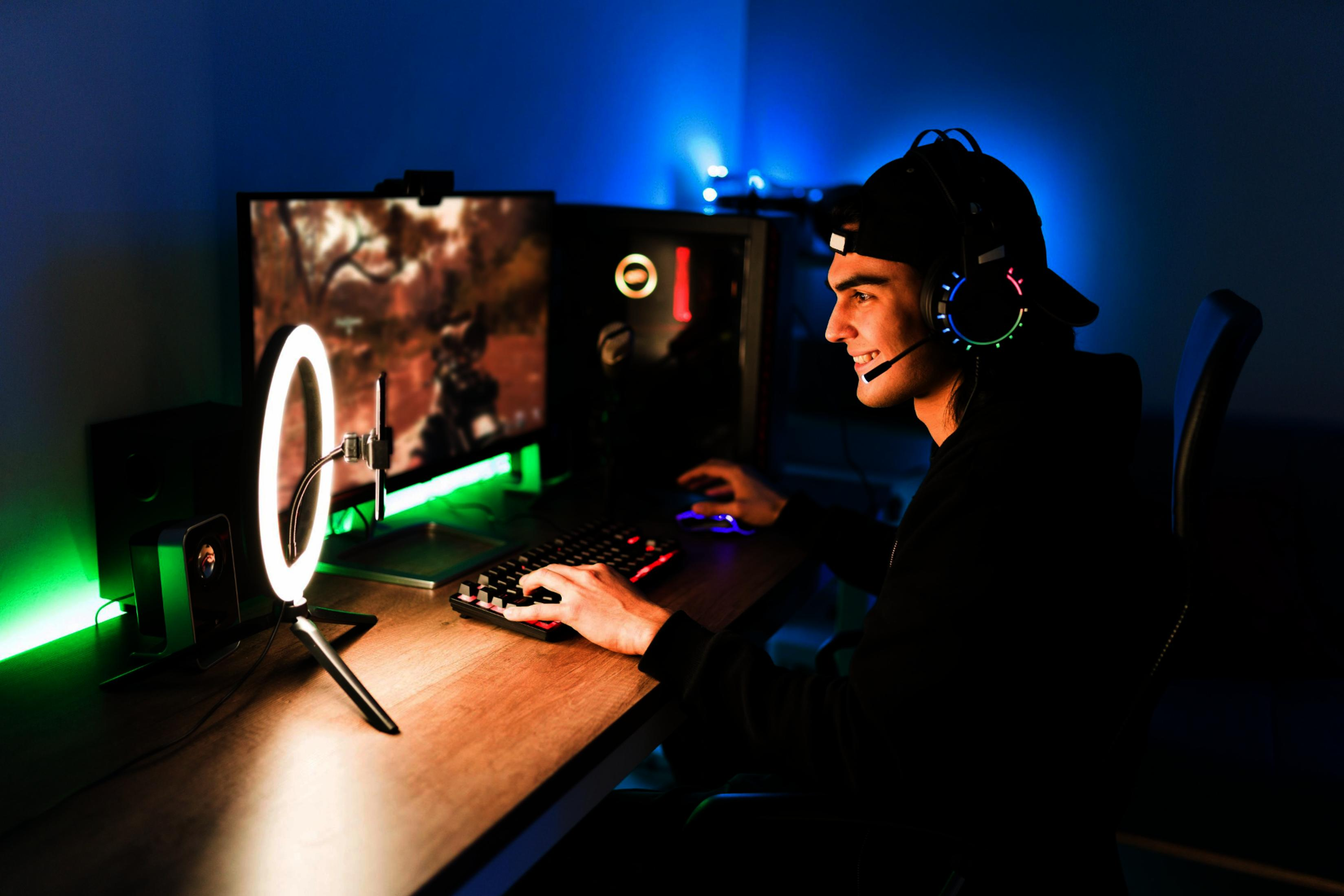 Un hombre con auriculares juega en un PC, iluminado por un aro de luz.