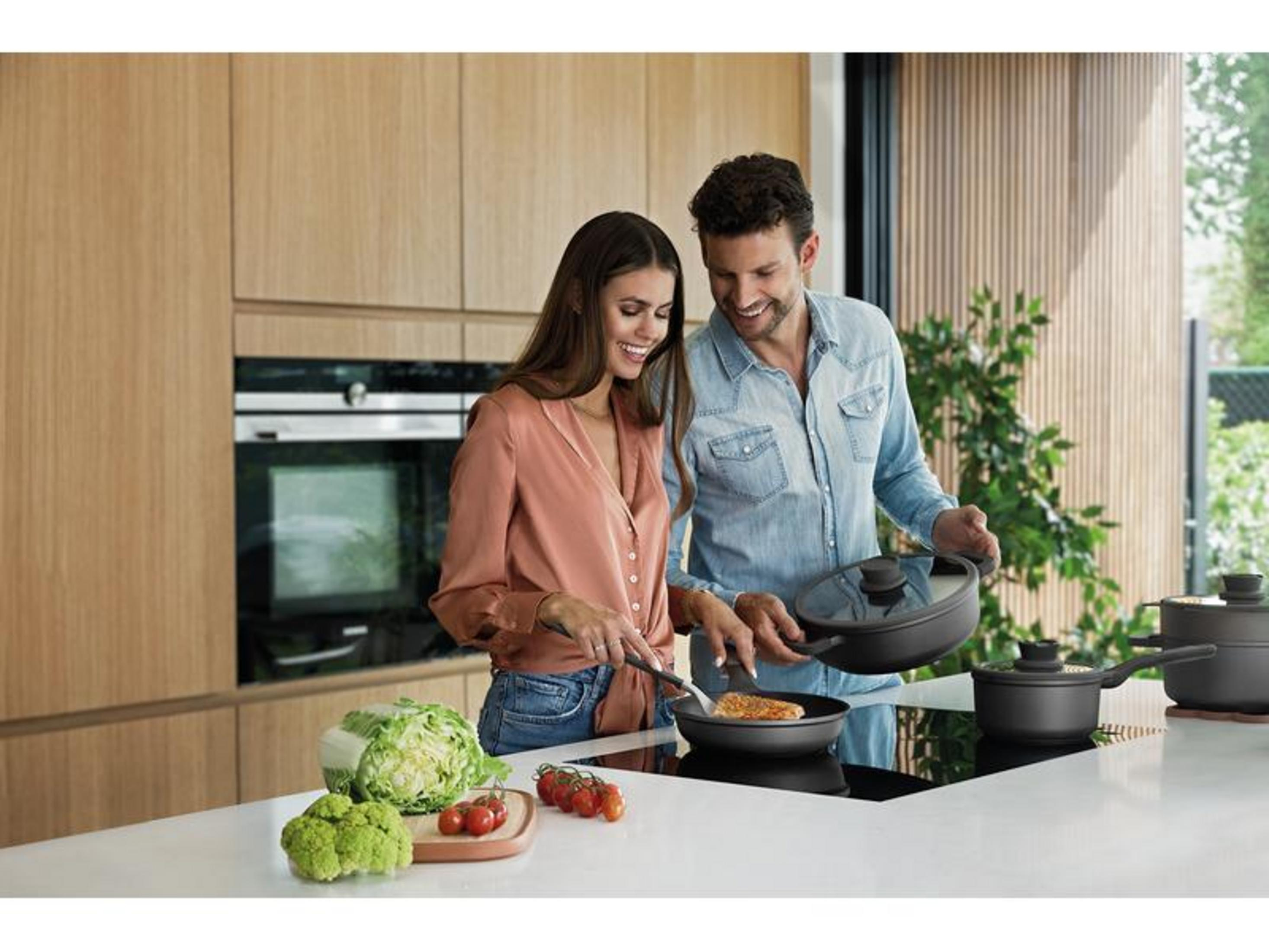 Een stel kookt samen in een moderne keuken met houten elementen.
