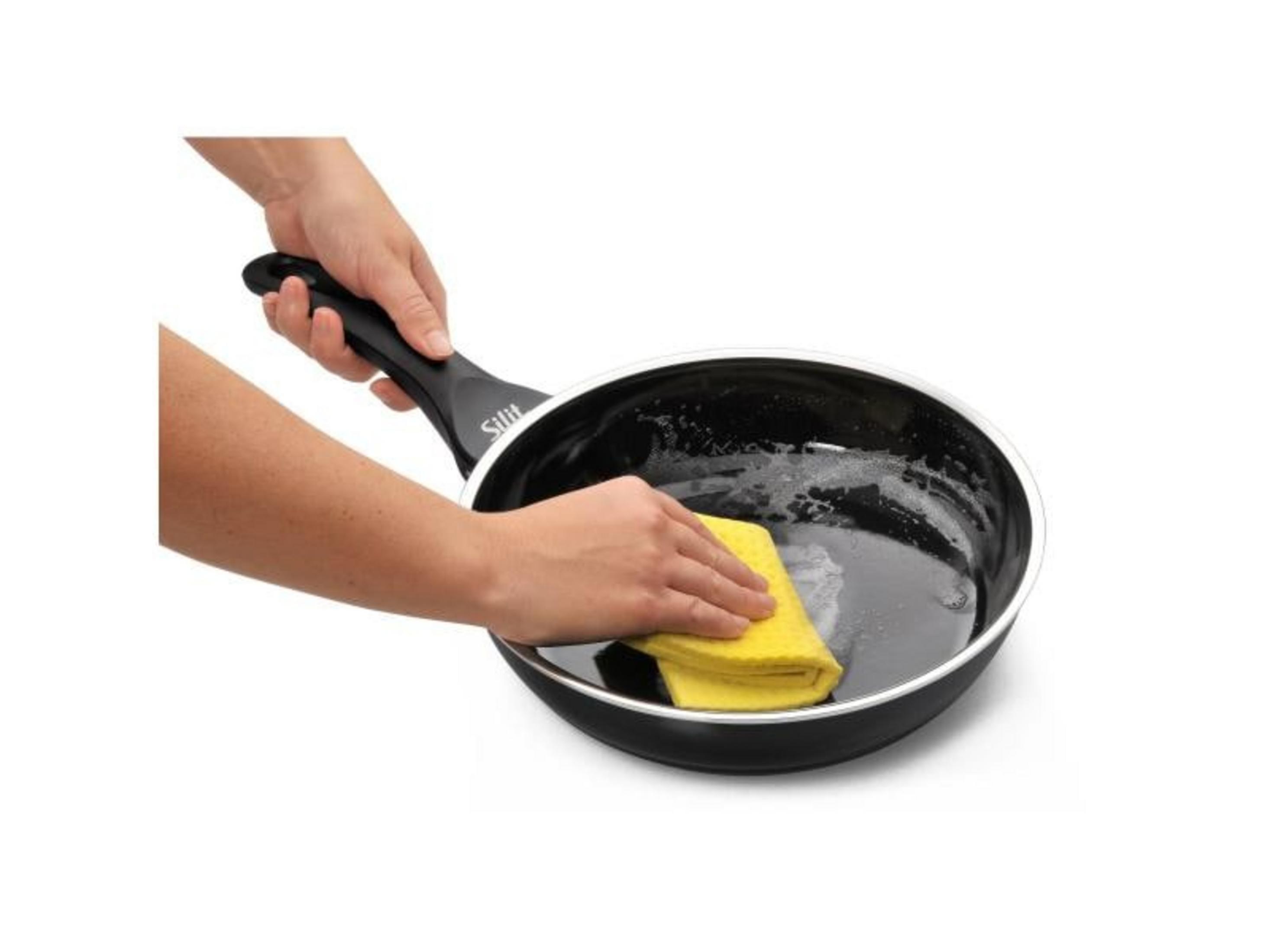 Hände reinigen eine schwarze Pfanne mit einem gelben Schwamm.