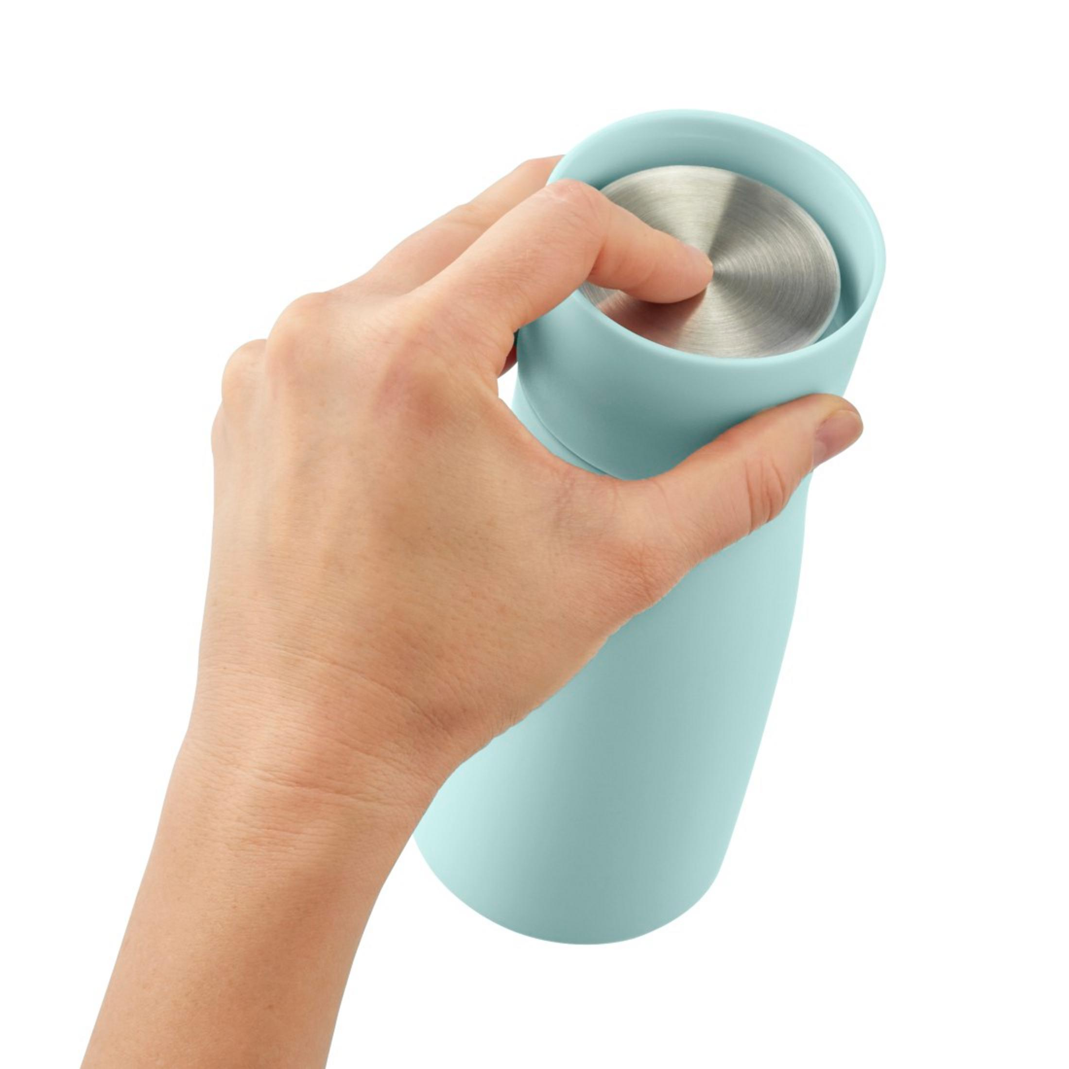 Eine Hand hält einen hellblauen Becher mit silbernem Deckel.