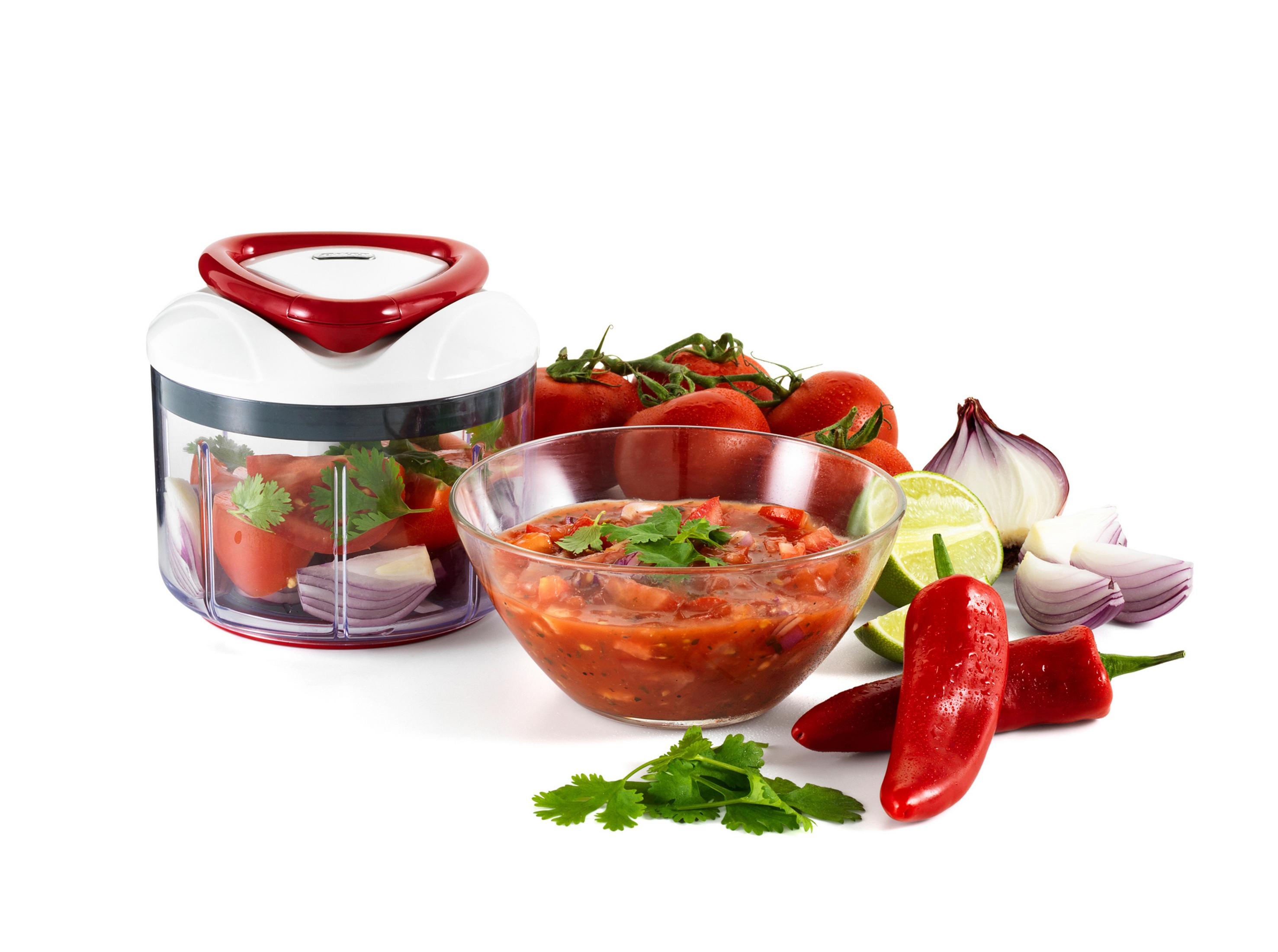 Un tritatutto manuale con pomodori, cipolle, lime e peperoncini per salsa.