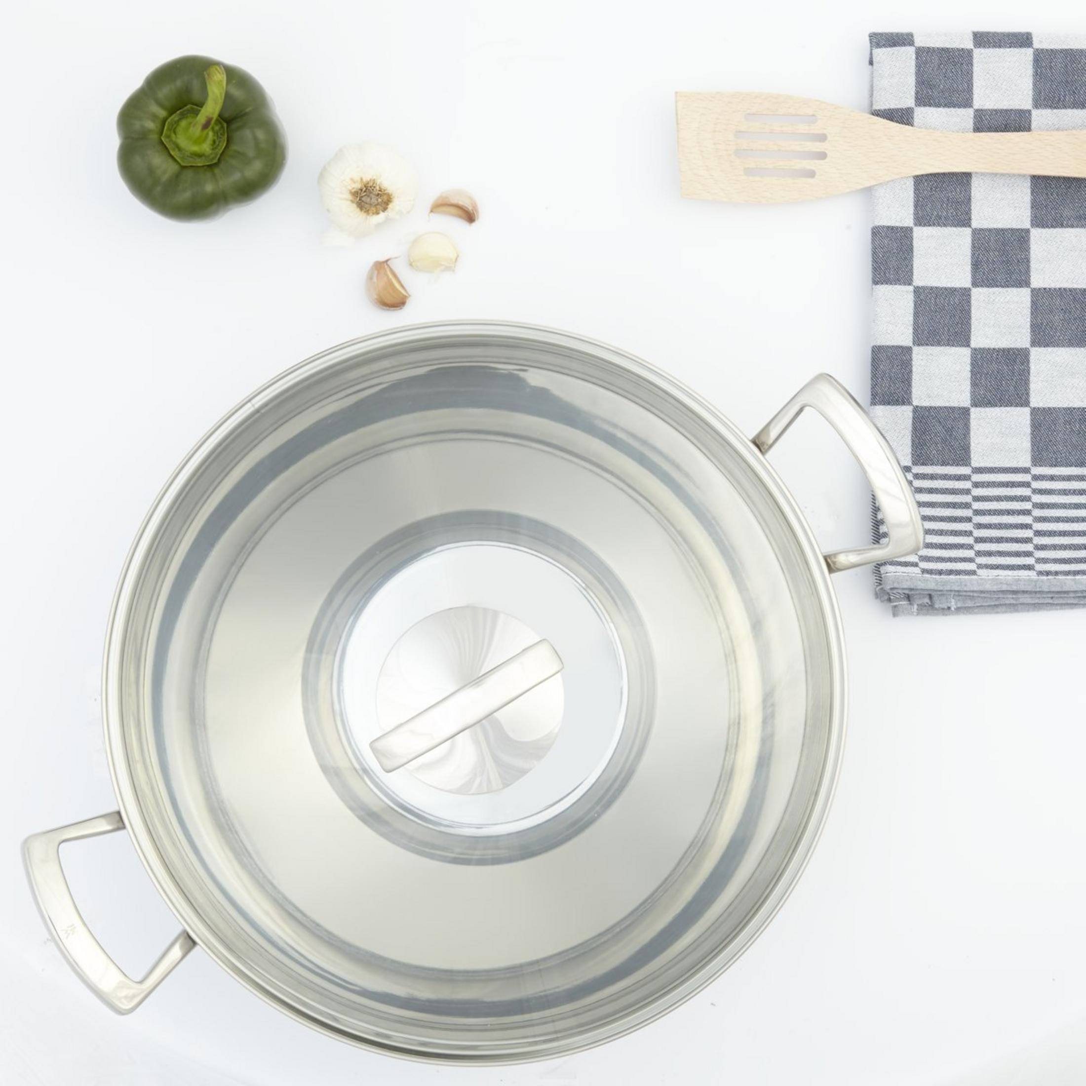 Top-Ansicht eines Edelstahltopfes mit Deckel, daneben ein grüner Paprika, Knoblauch und ein Holzlöffel.