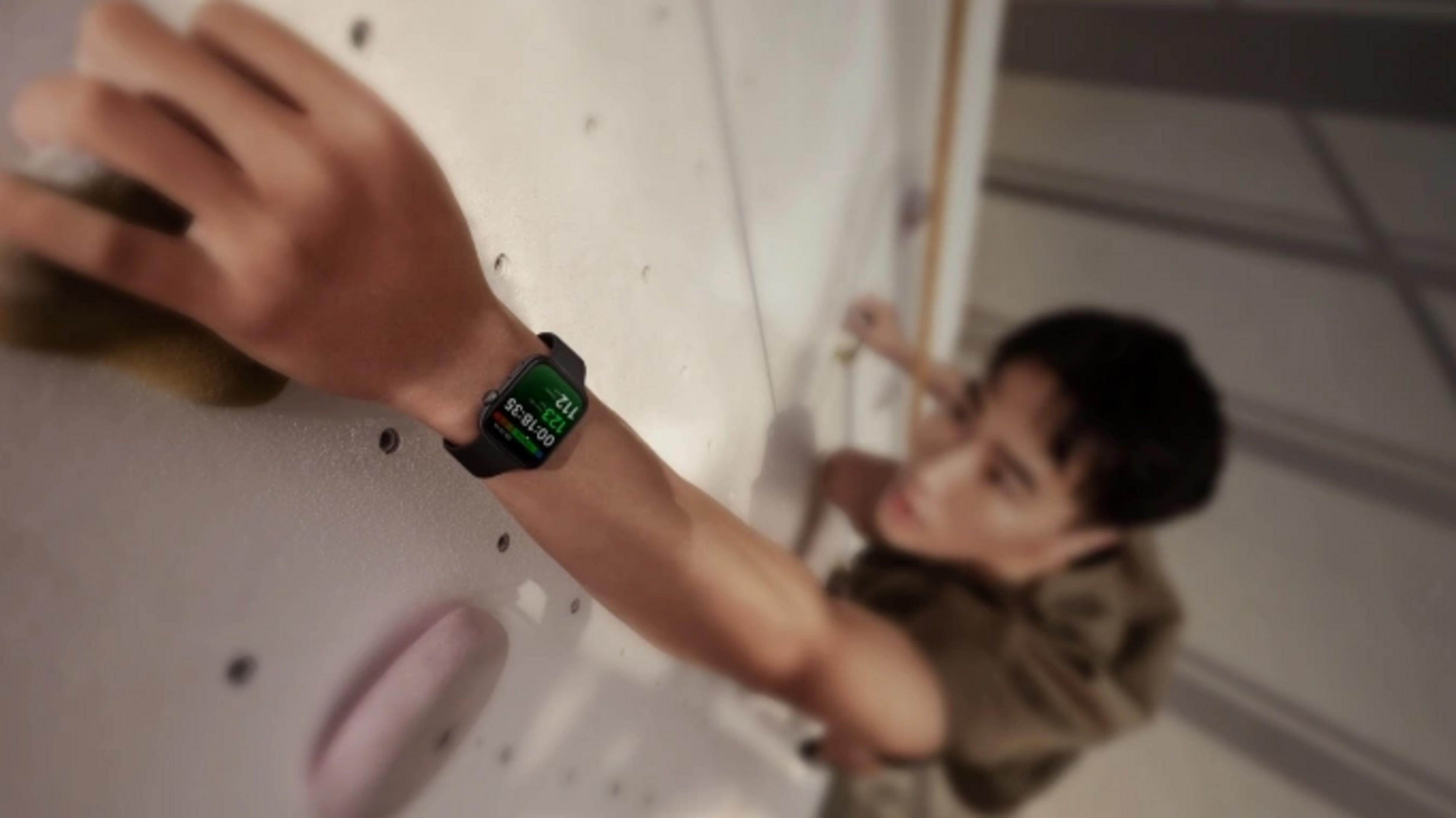 Een man klimt tegen een muur, draagt een smartwatch met trainingsgegevens.