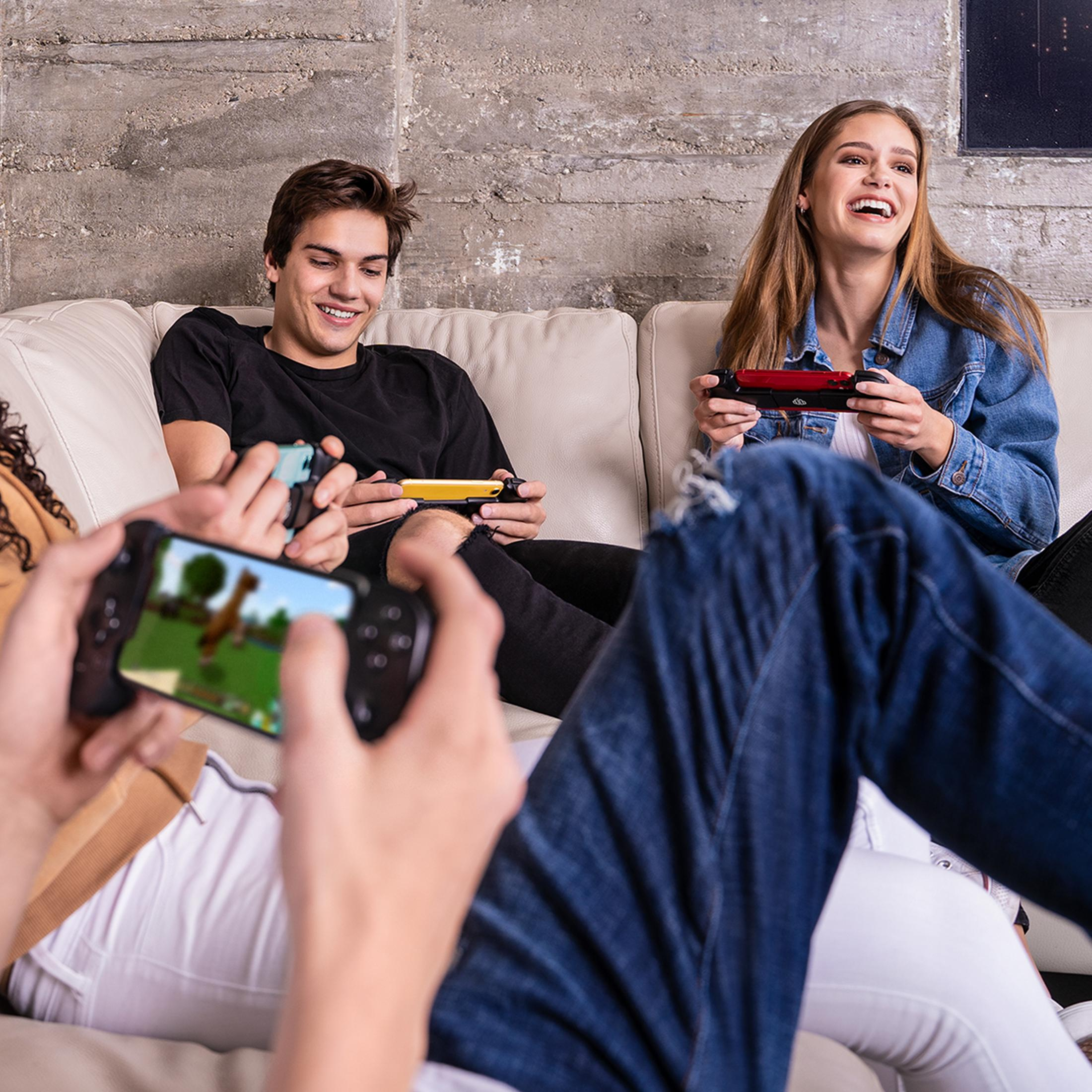 Vier vrienden spelen videogames op een bank met handheld consoles.