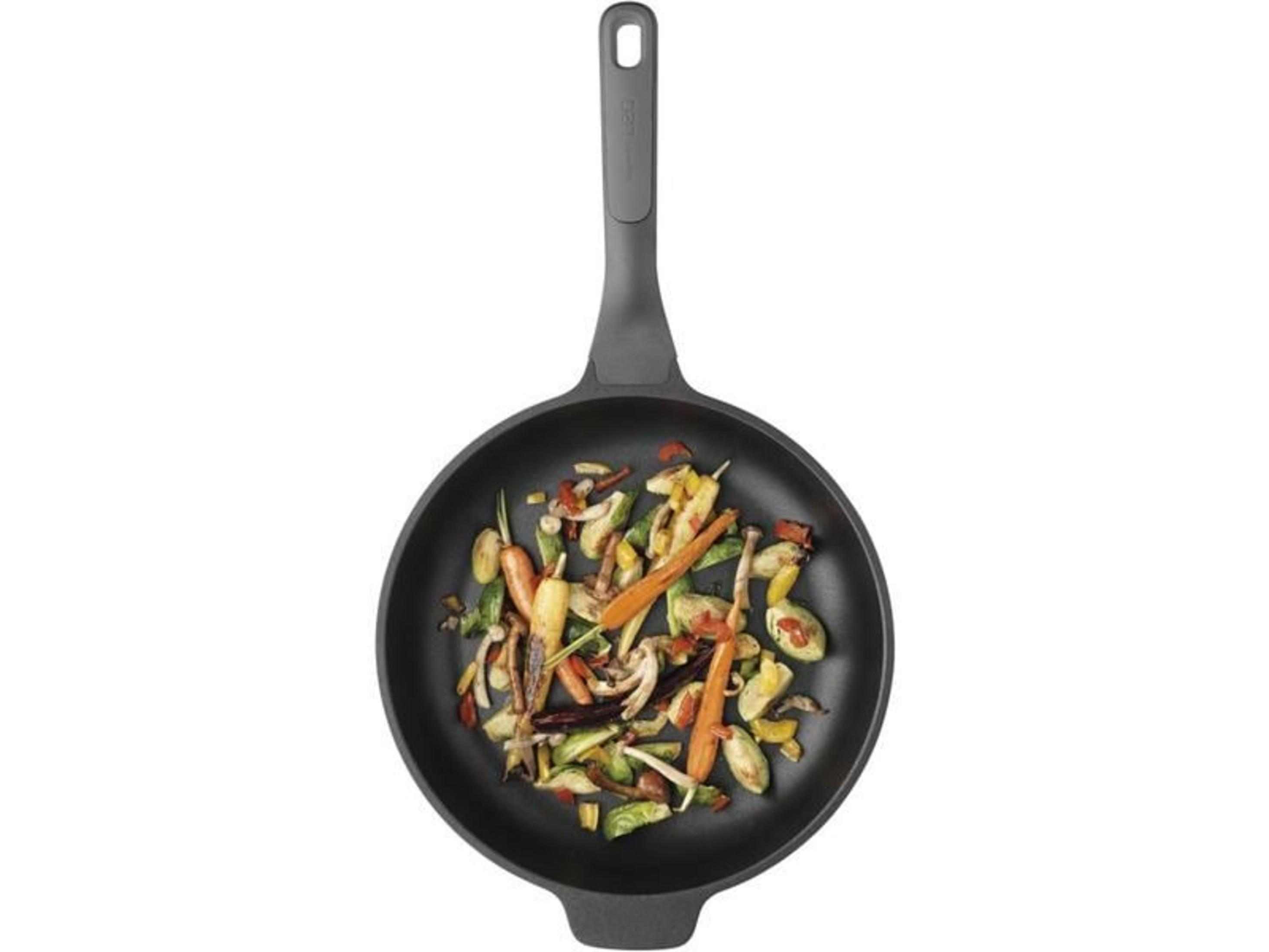 Groenten worden gebakken in een zwarte koekenpan. Bevat wortelen, paprika en champignons.
