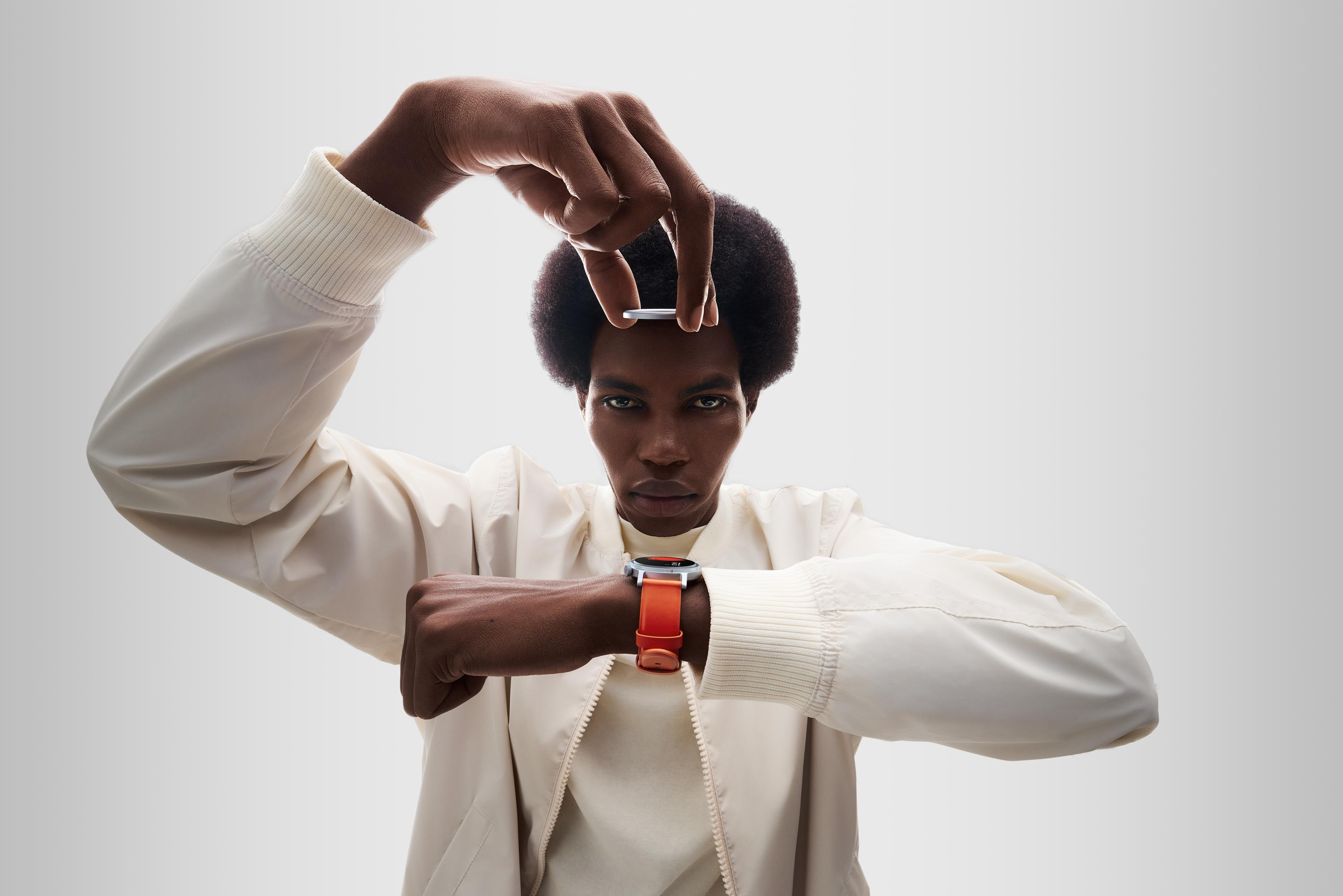 Mężczyzna z krótkimi włosami i smartwatchem trzyma monetę.