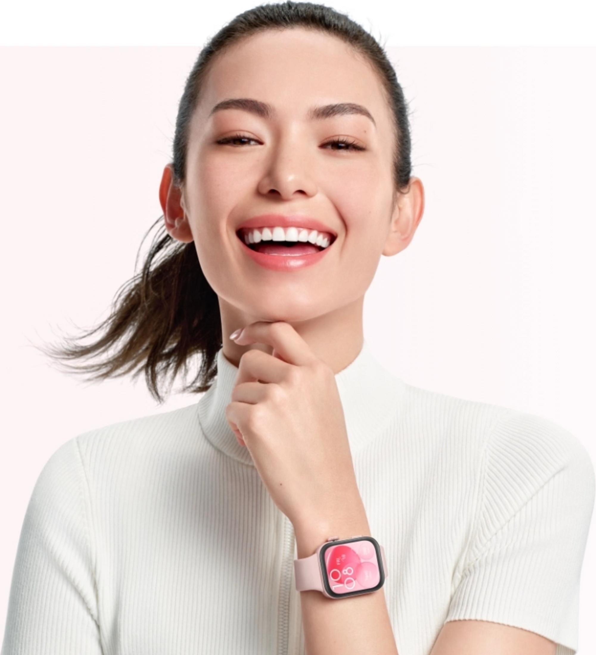Frau mit einem rosa Smartwatch am Handgelenk, die ein weißes Oberteil trägt.