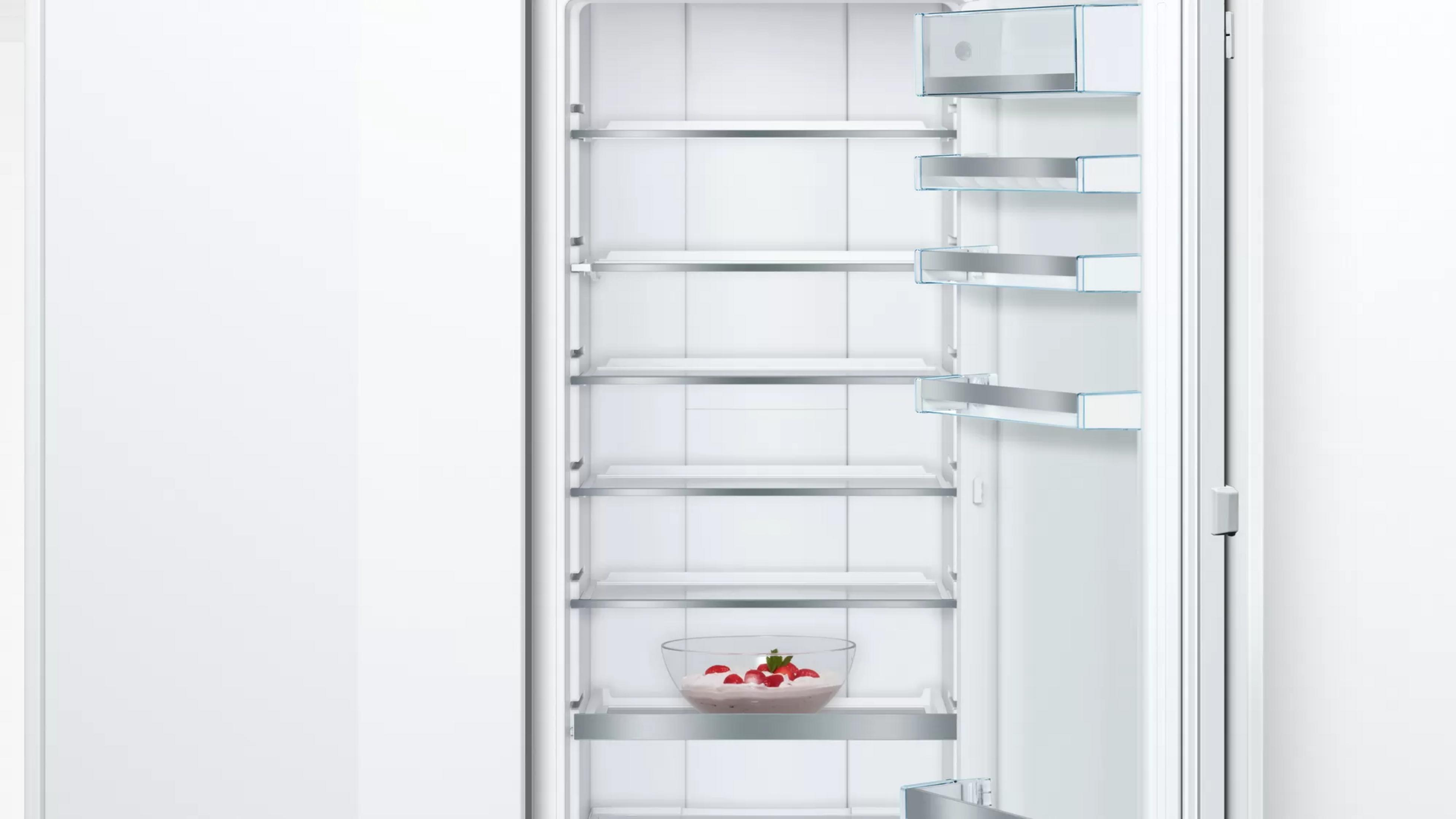 Ein leerer Kühlschrank mit einer Schale Dessert mit Erdbeeren auf dem unteren Regal.