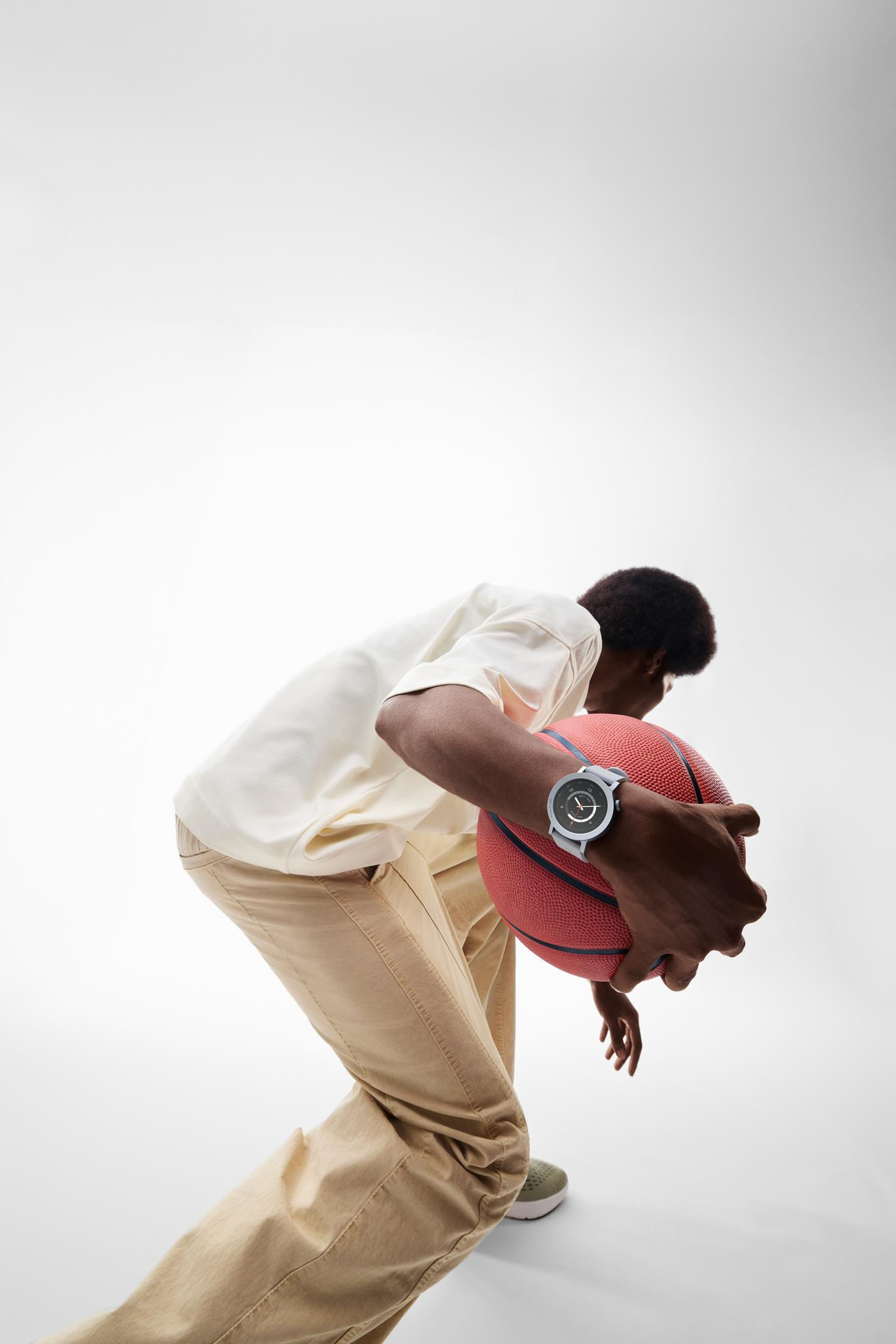 Mężczyzna trzymający piłkę do koszykówki, noszący zegarek.