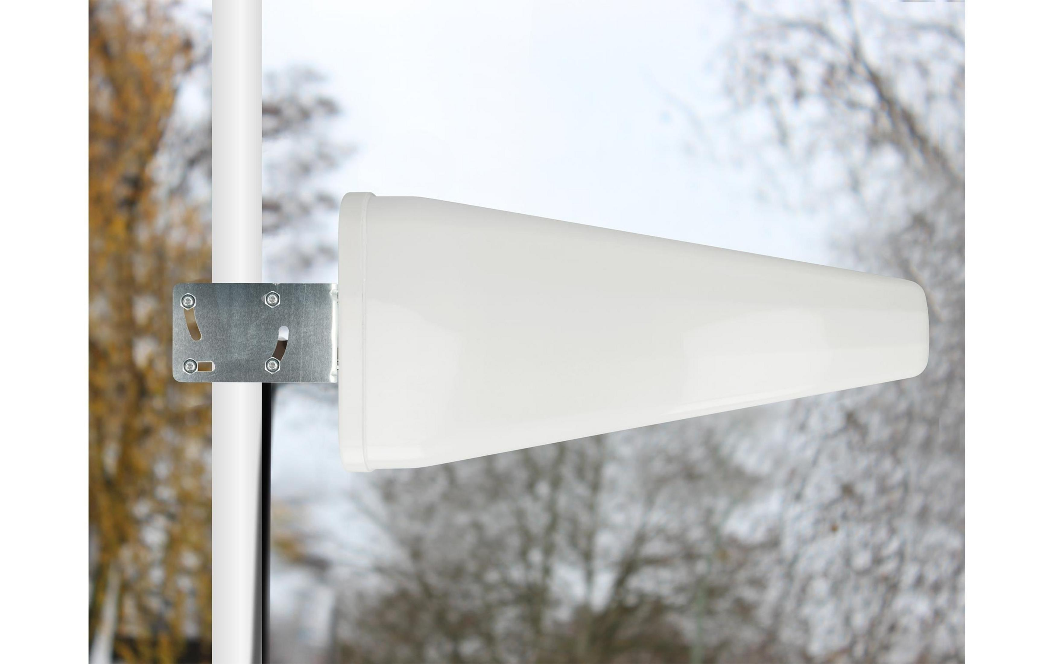 Un'antenna direzionale bianca, montata su un palo, con alberi sullo sfondo.
