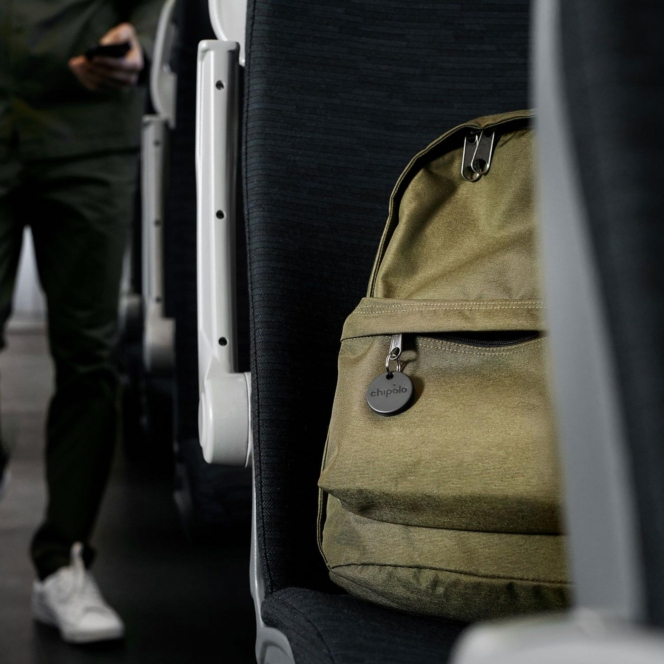 Green backpack with Chipolo tag on a public transport seat.