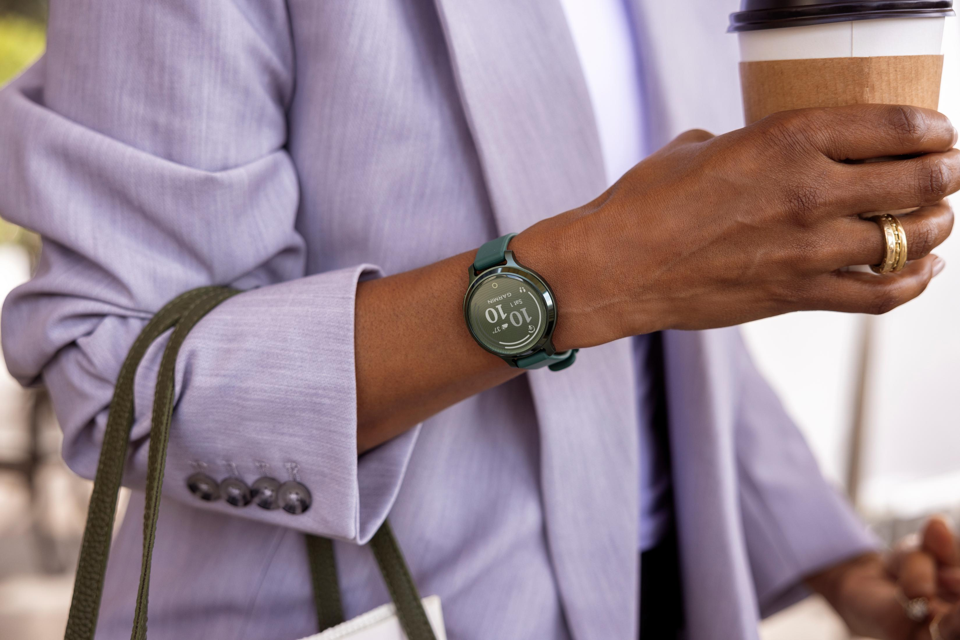 Persona con blazer lila sostiene taza de café. Lleva reloj y anillos.