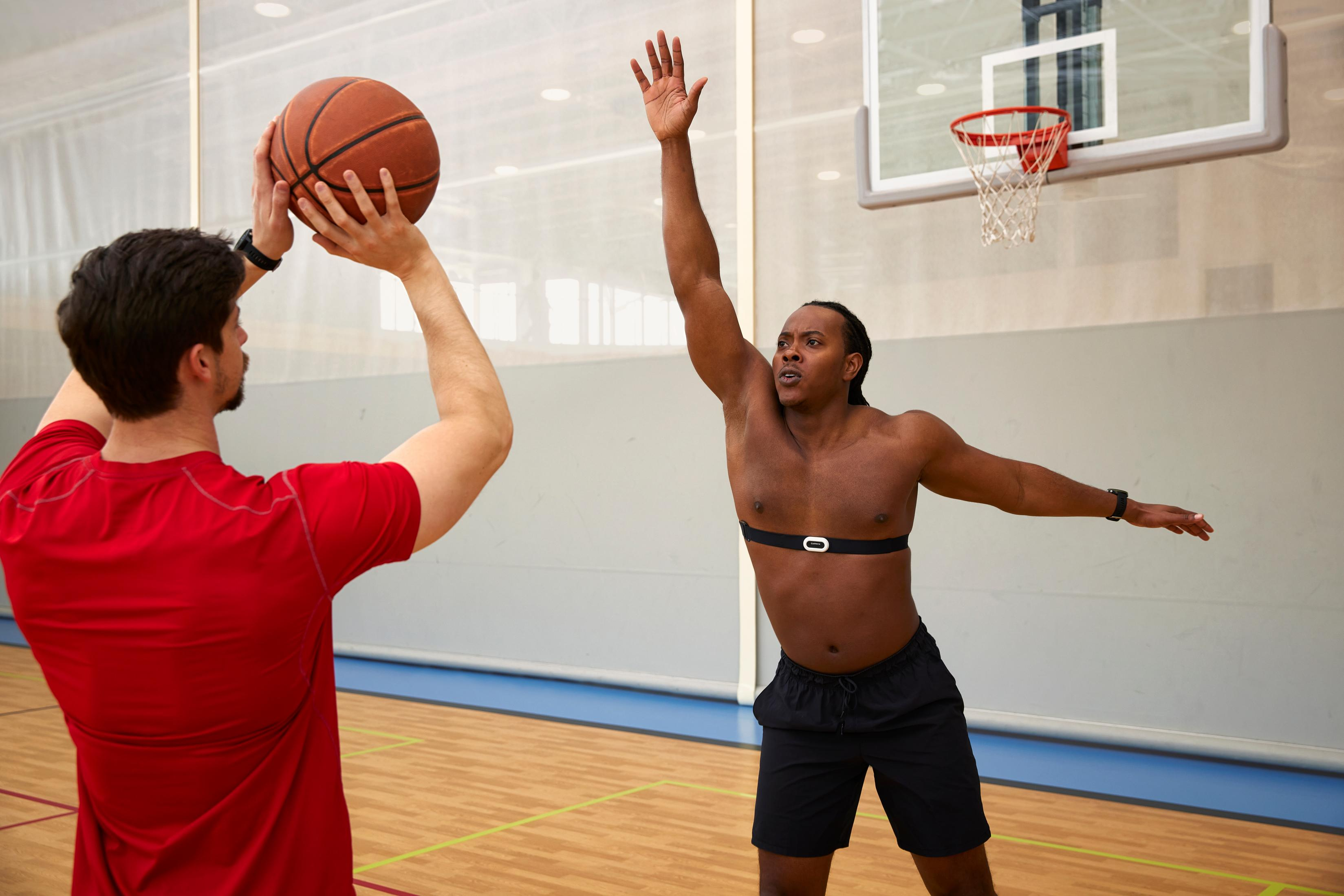 Zwei Männer spielen Basketball. Einer wirft den Ball, der andere blockt.