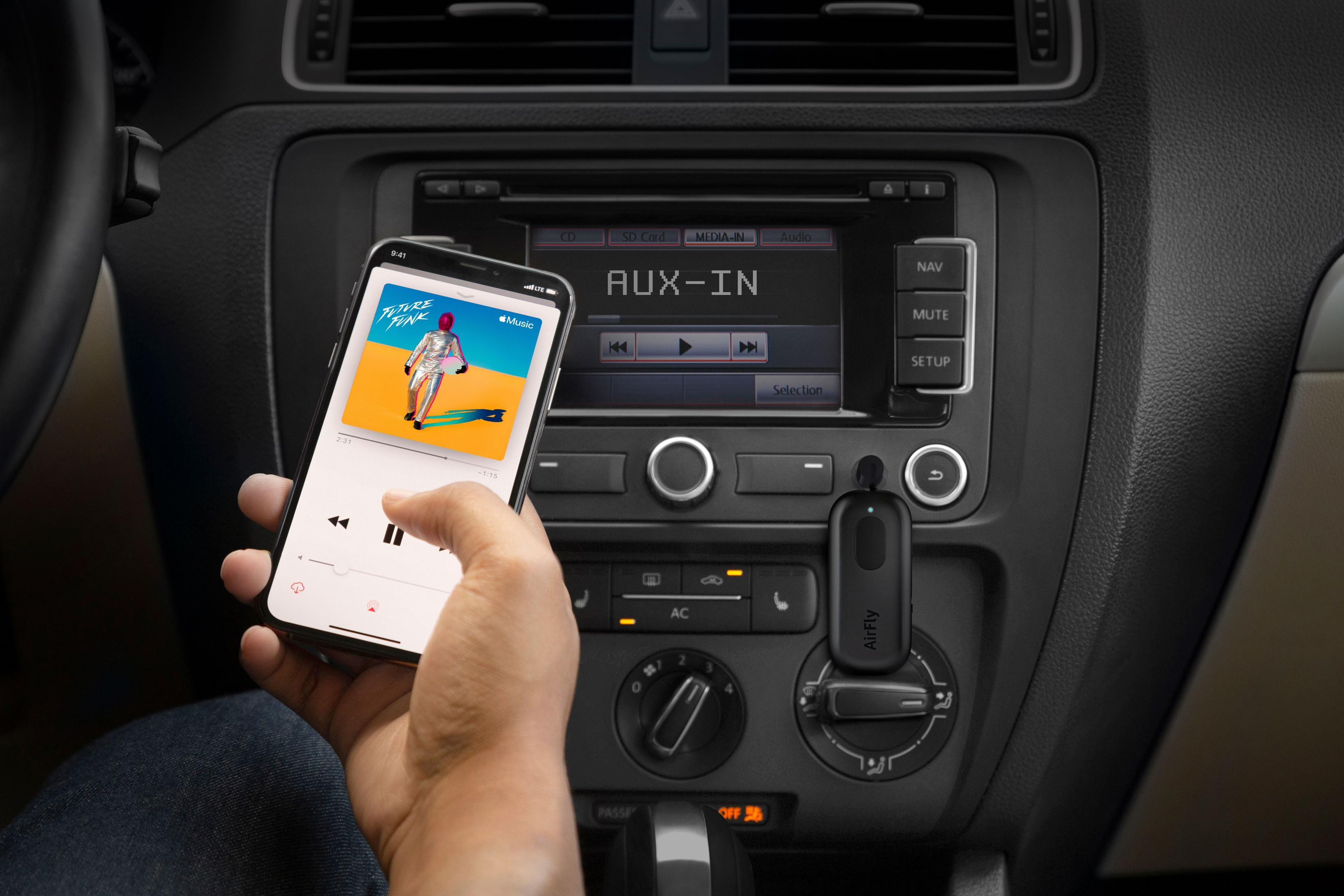 Hand hält Smartphone mit Musik-App vor einem Auto-Radio. AUX-IN angezeigt.