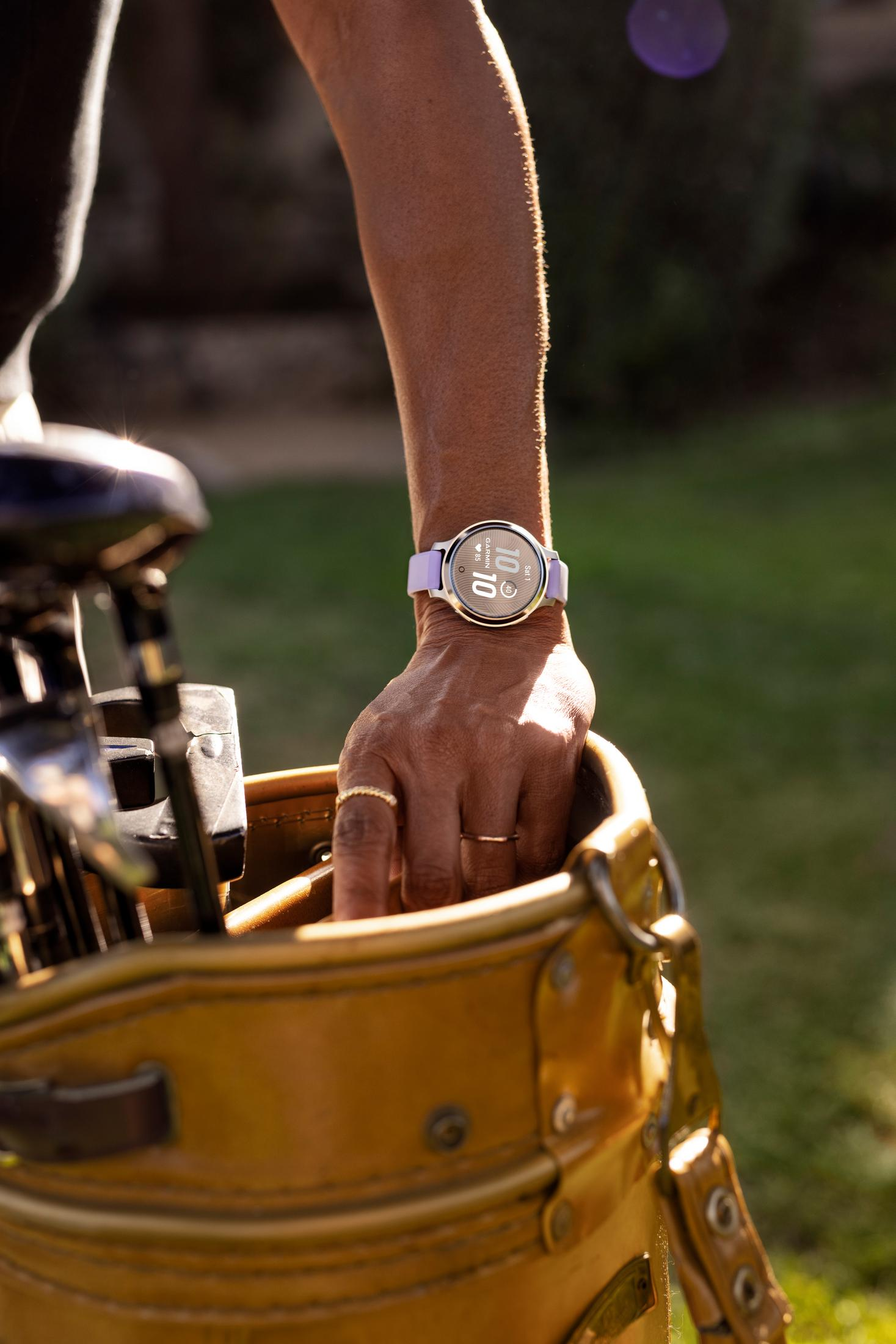 Eine Hand mit einer lilafarbenen Smartwatch greift in eine gelbe Golftasche.