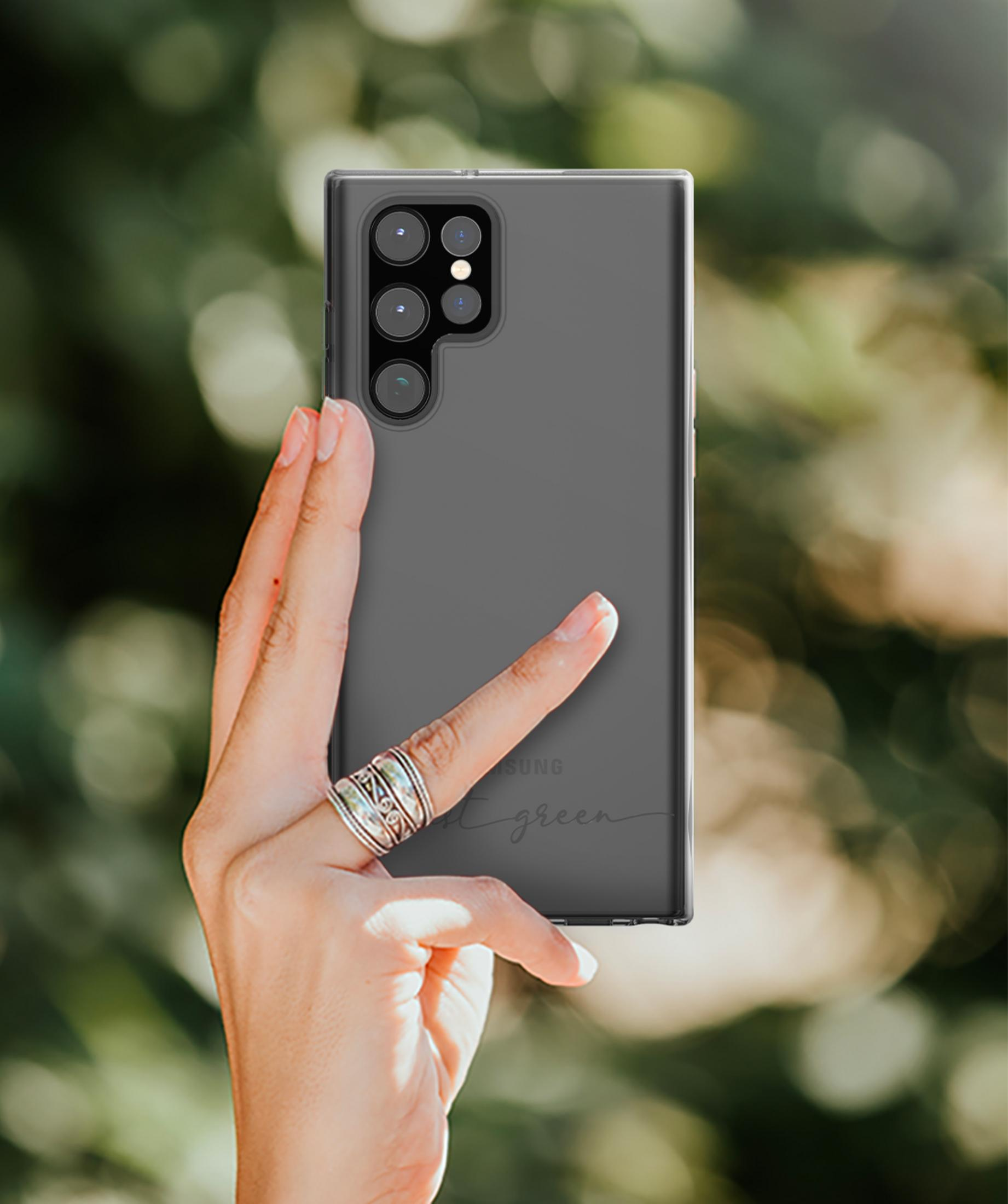 Eine Hand hält ein graues Handy mit vier Kameras. Der Hintergrund ist unscharf.