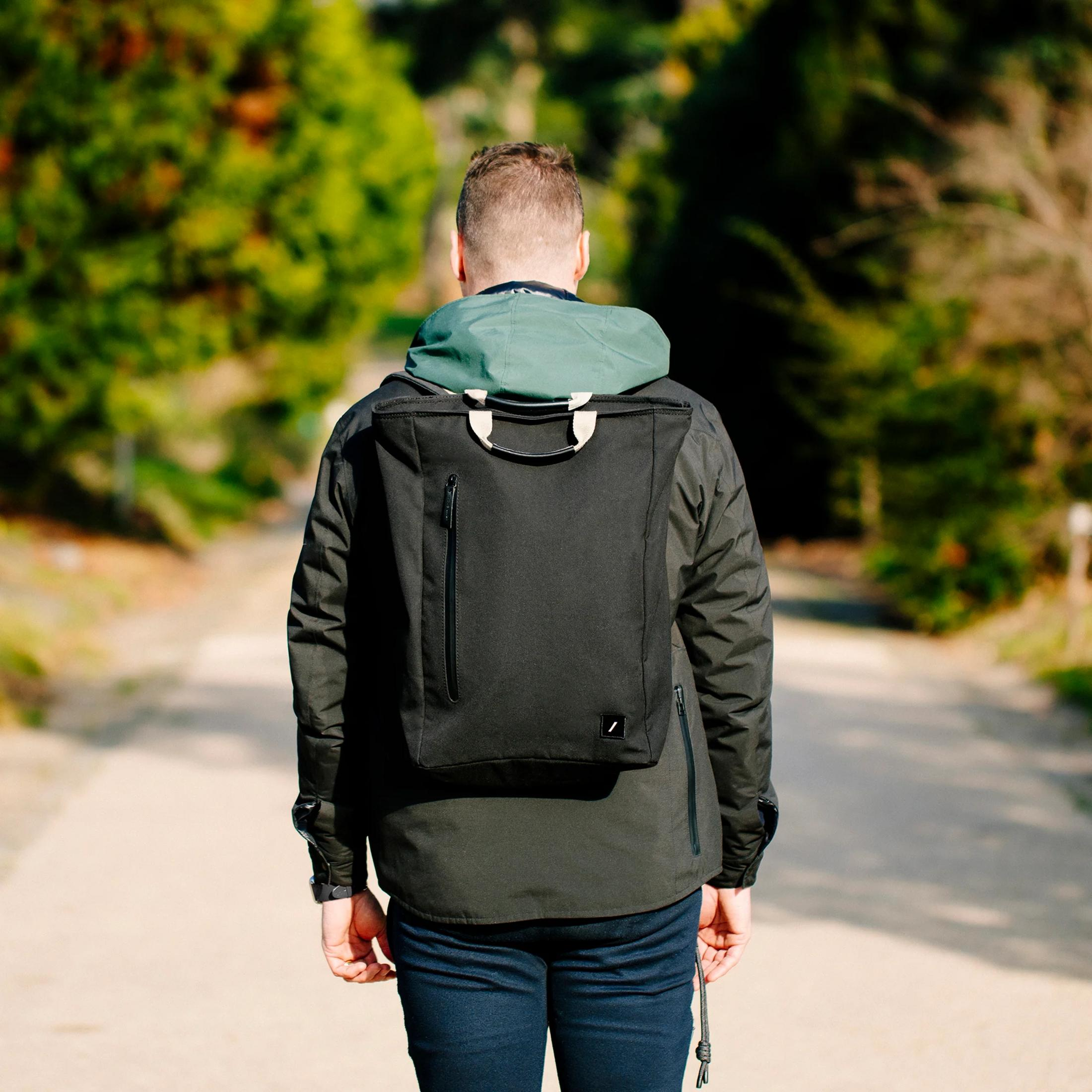 Mann mit Rucksack geht auf einem Weg durch Bäume.