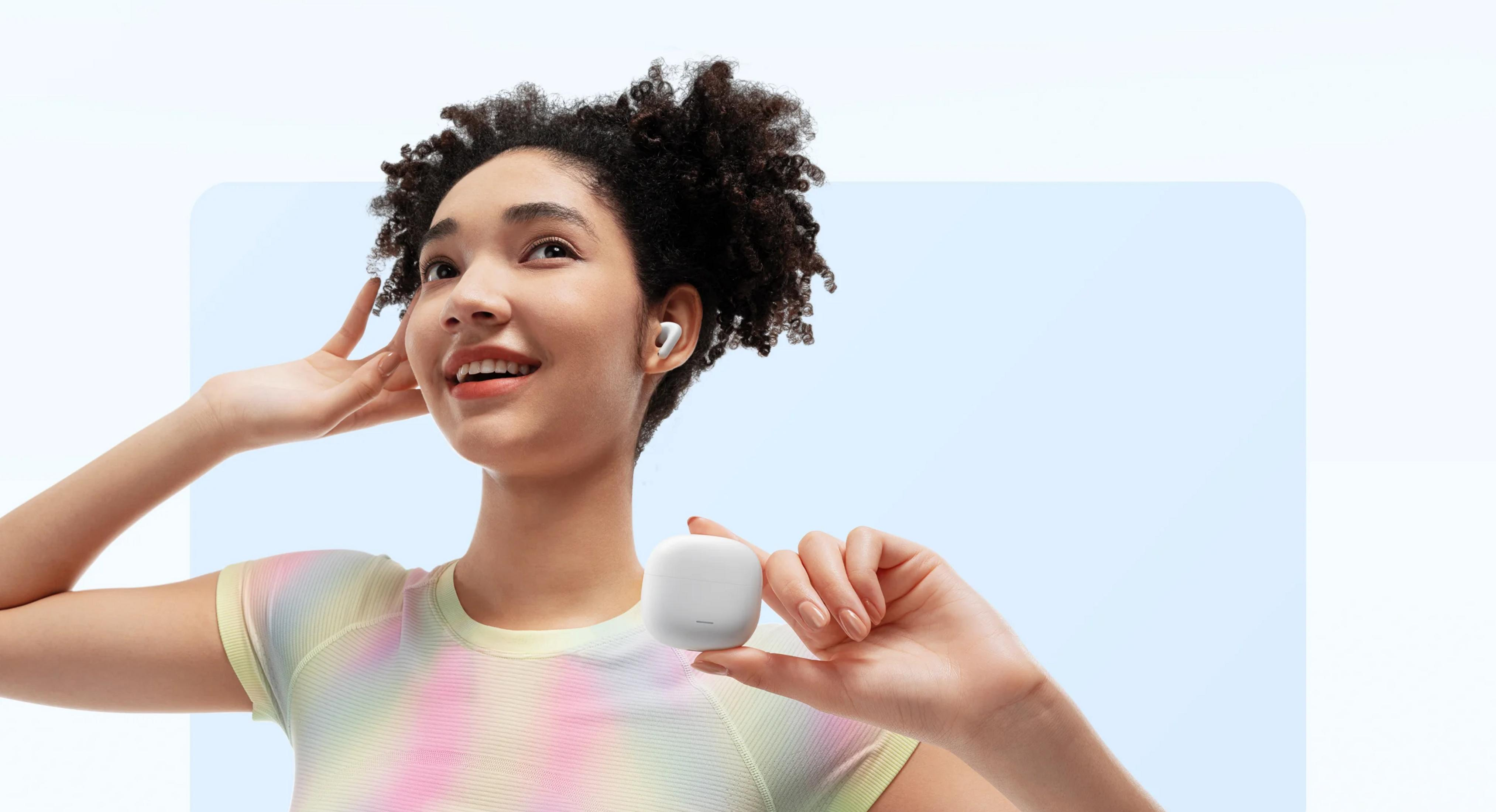 Kobieta trzyma białe etui na słuchawki, nosi kolorową koszulkę.