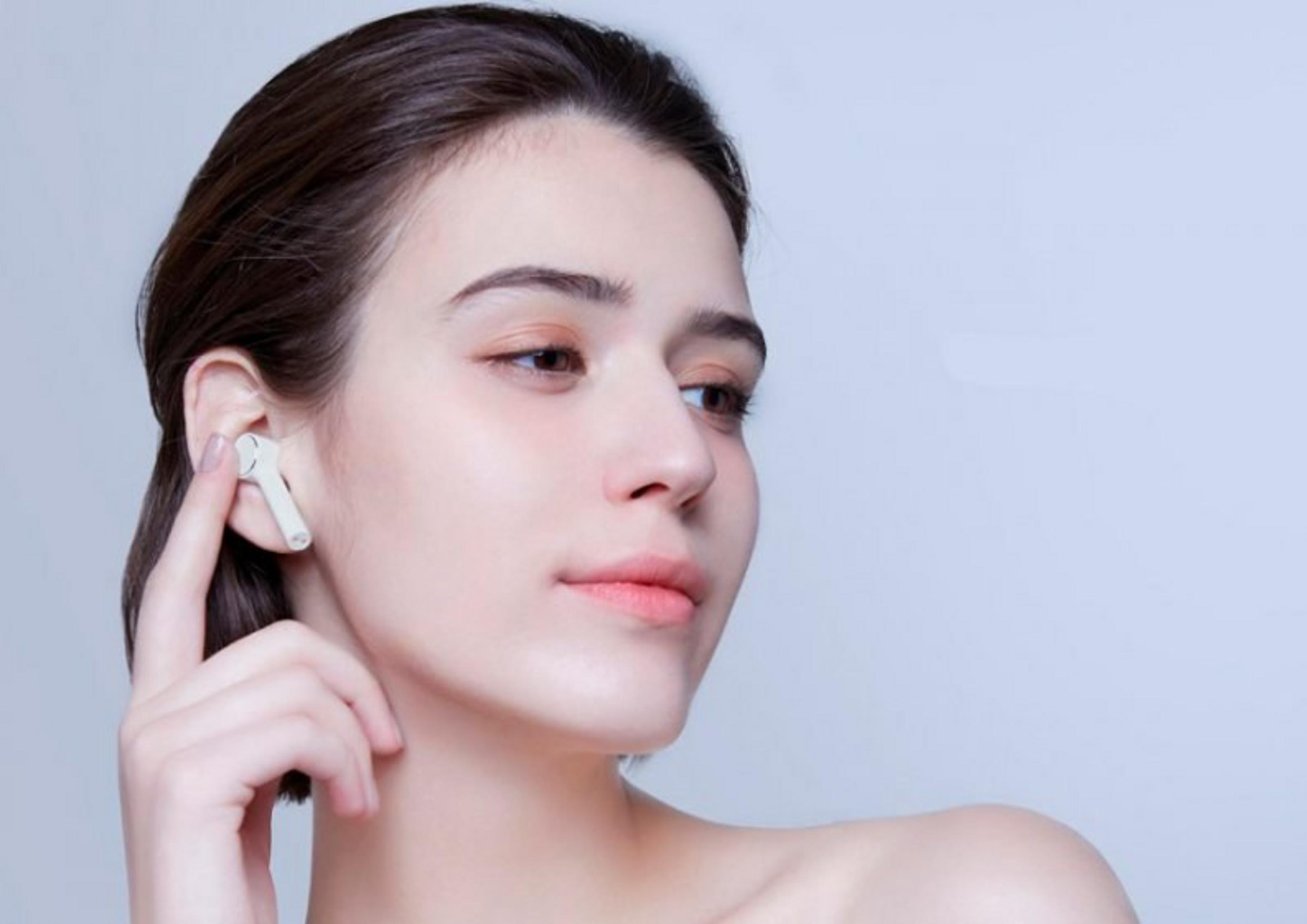 Una donna con un auricolare bianco nell'orecchio, che gira leggermente il viso.