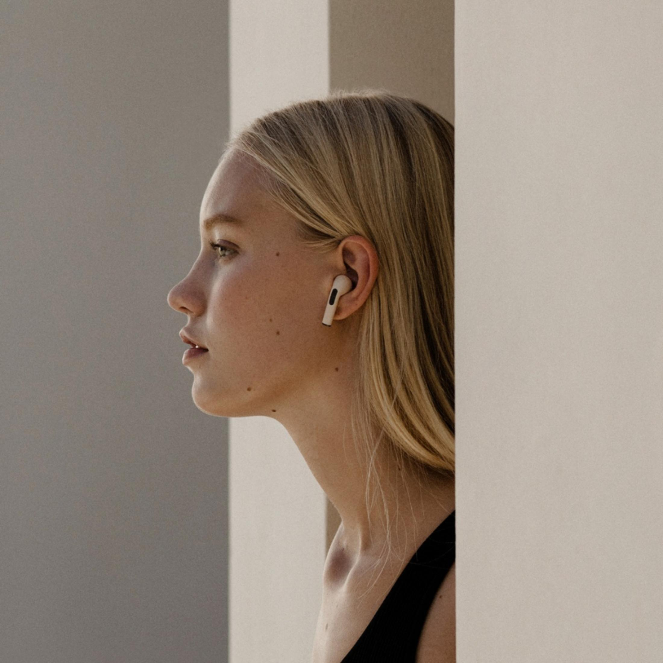 Blondynka w słuchawce, widziana z profilu, patrząca w lewo.