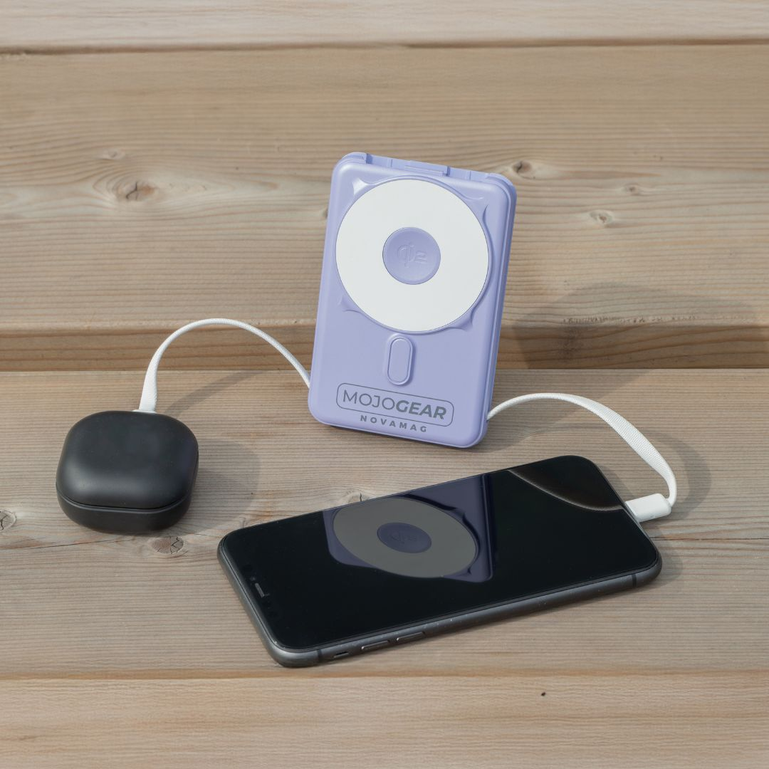 Ein lila Ladegerät und ein schwarzes Smartphone mit Kabeln auf Holz.