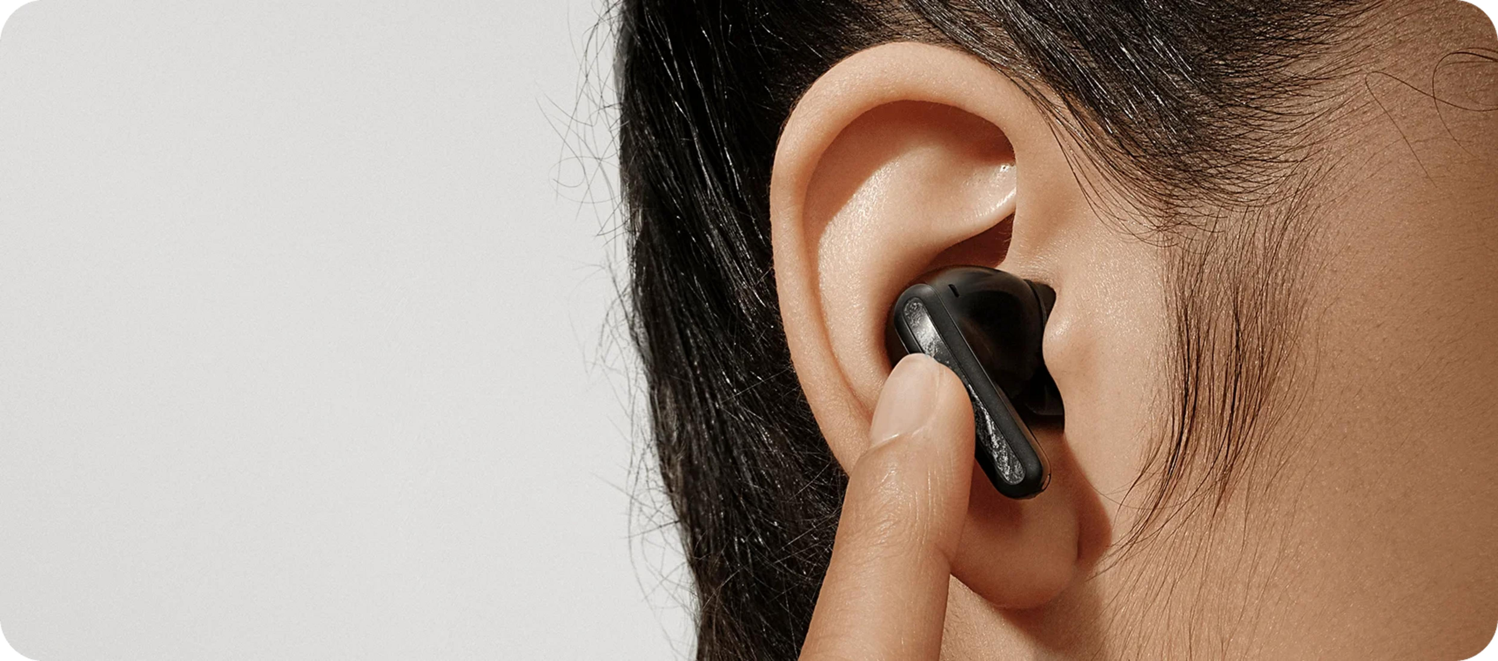 Dłoń wkłada czarny douszny do ucha.