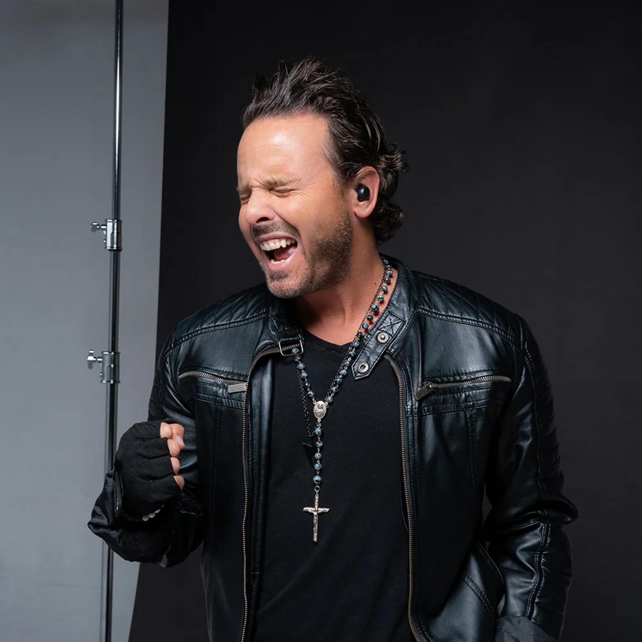 Mężczyzna z zamkniętymi oczami w skórzanej kurtce, głośno śpiewa.