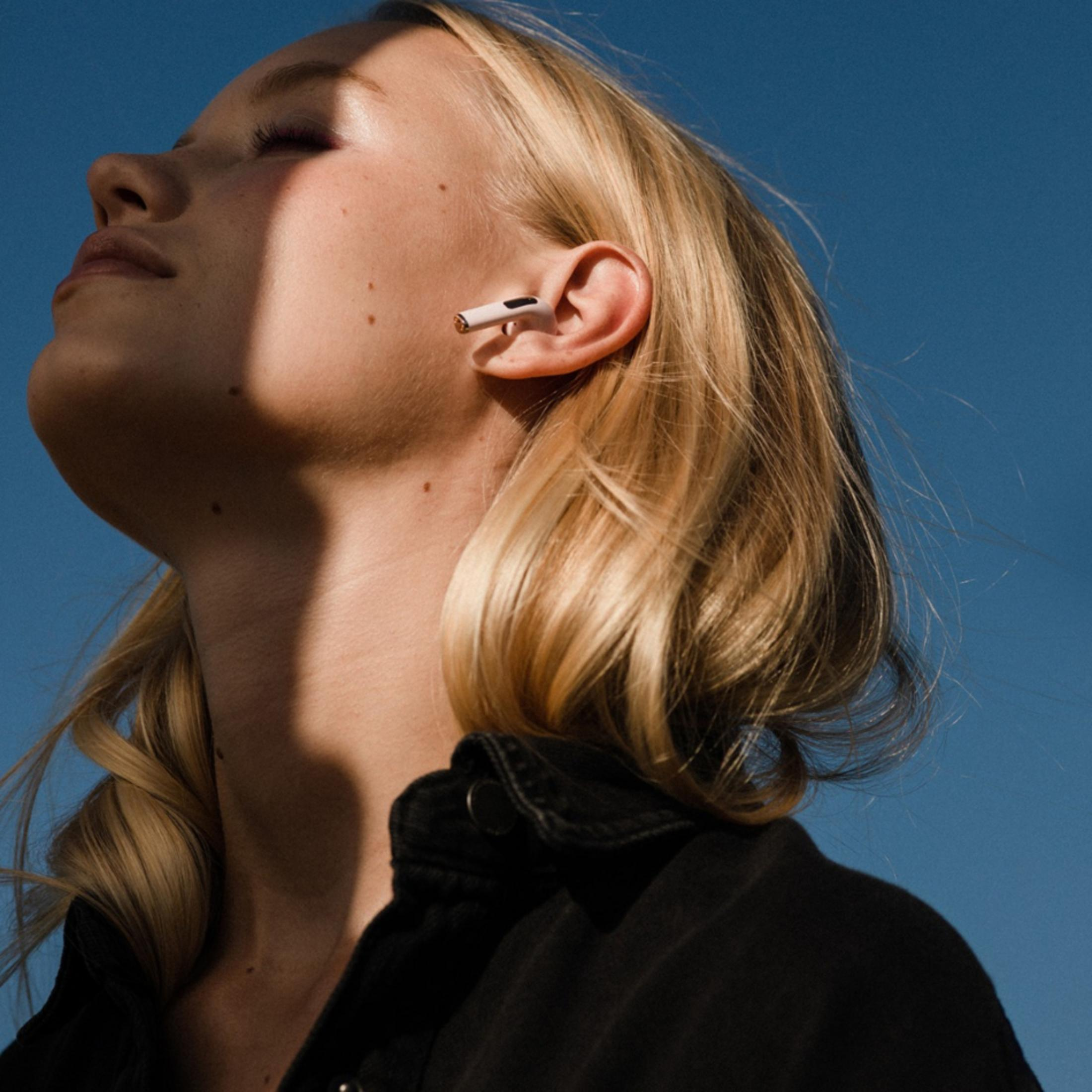 Eine Frau mit blonden Haaren und Kopfhörern im blauen Himmel.
