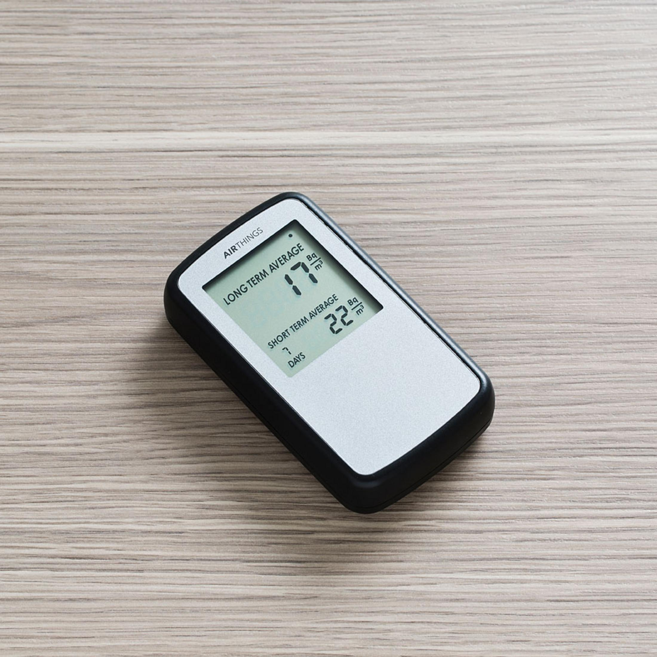 Un dispositivo Airthings che mostra medie a lungo e breve termine su un tavolo di legno.