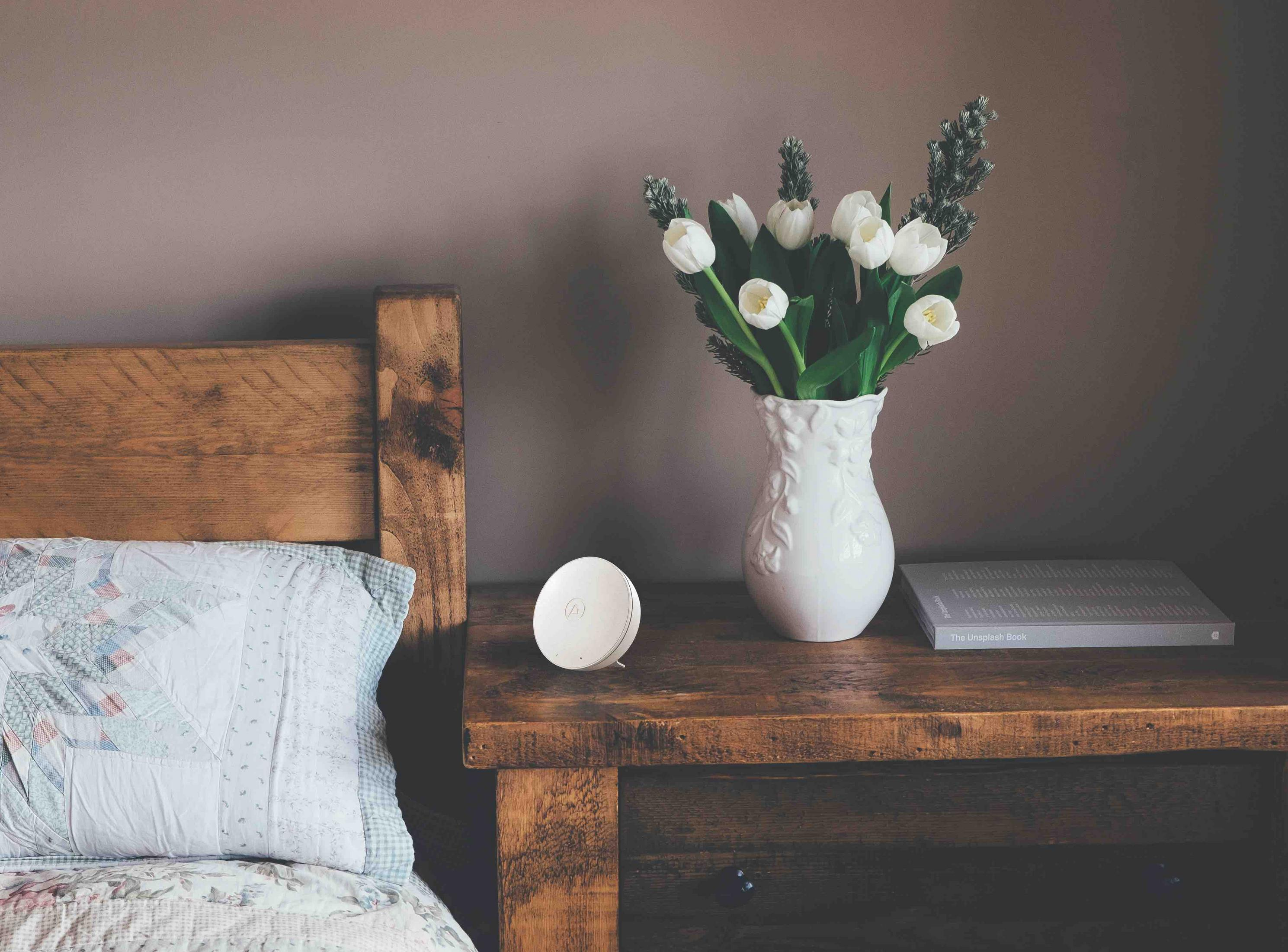 Holz Nachttisch mit weißer Vase, Tulpen, Buch und weißem Gerät.