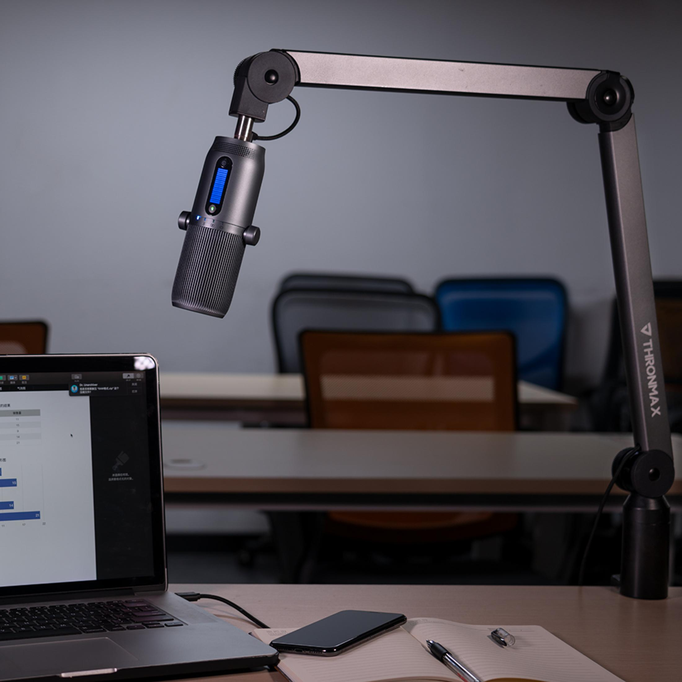Una scrivania con laptop, microfono e taccuino in un ufficio.