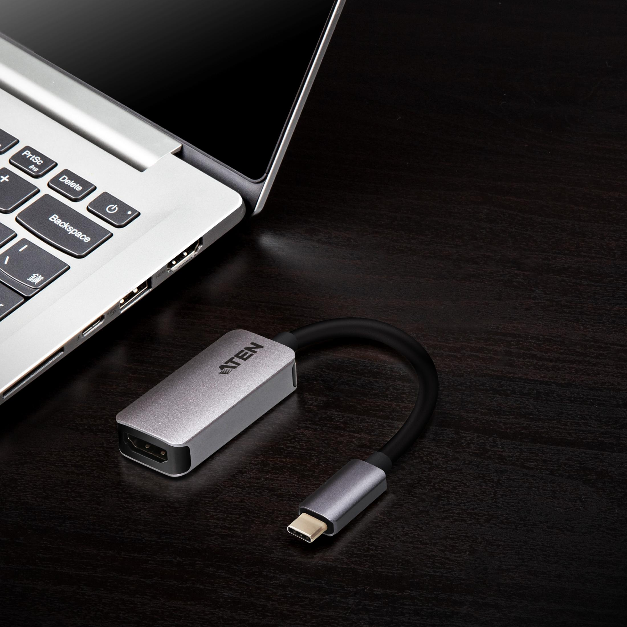 Ein silberner USB-C-Adapter mit HDMI-Anschluss liegt neben einem Laptop.