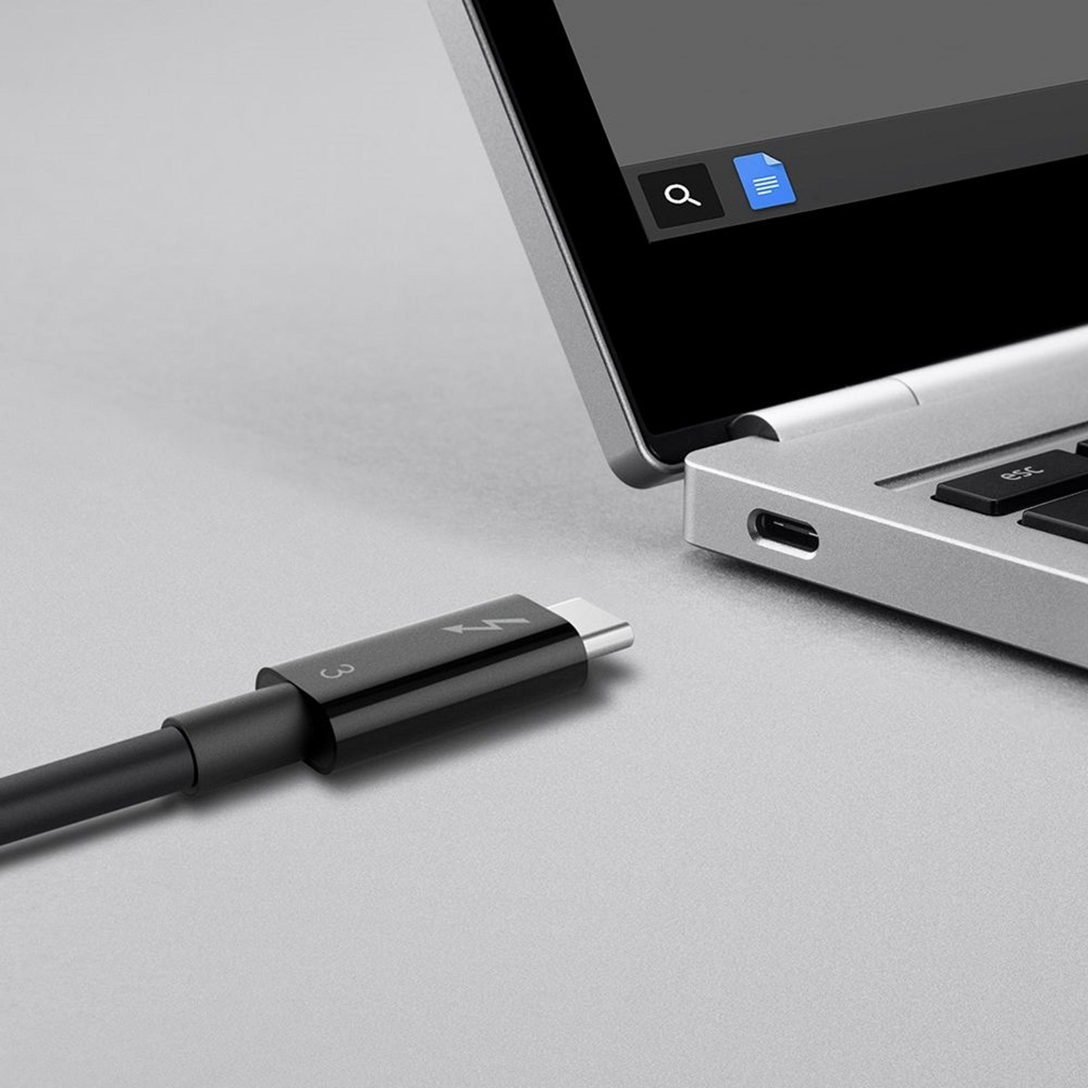 Ein schwarzes USB-C-Kabel mit Blitzsymbol neben einem geöffneten Laptop.